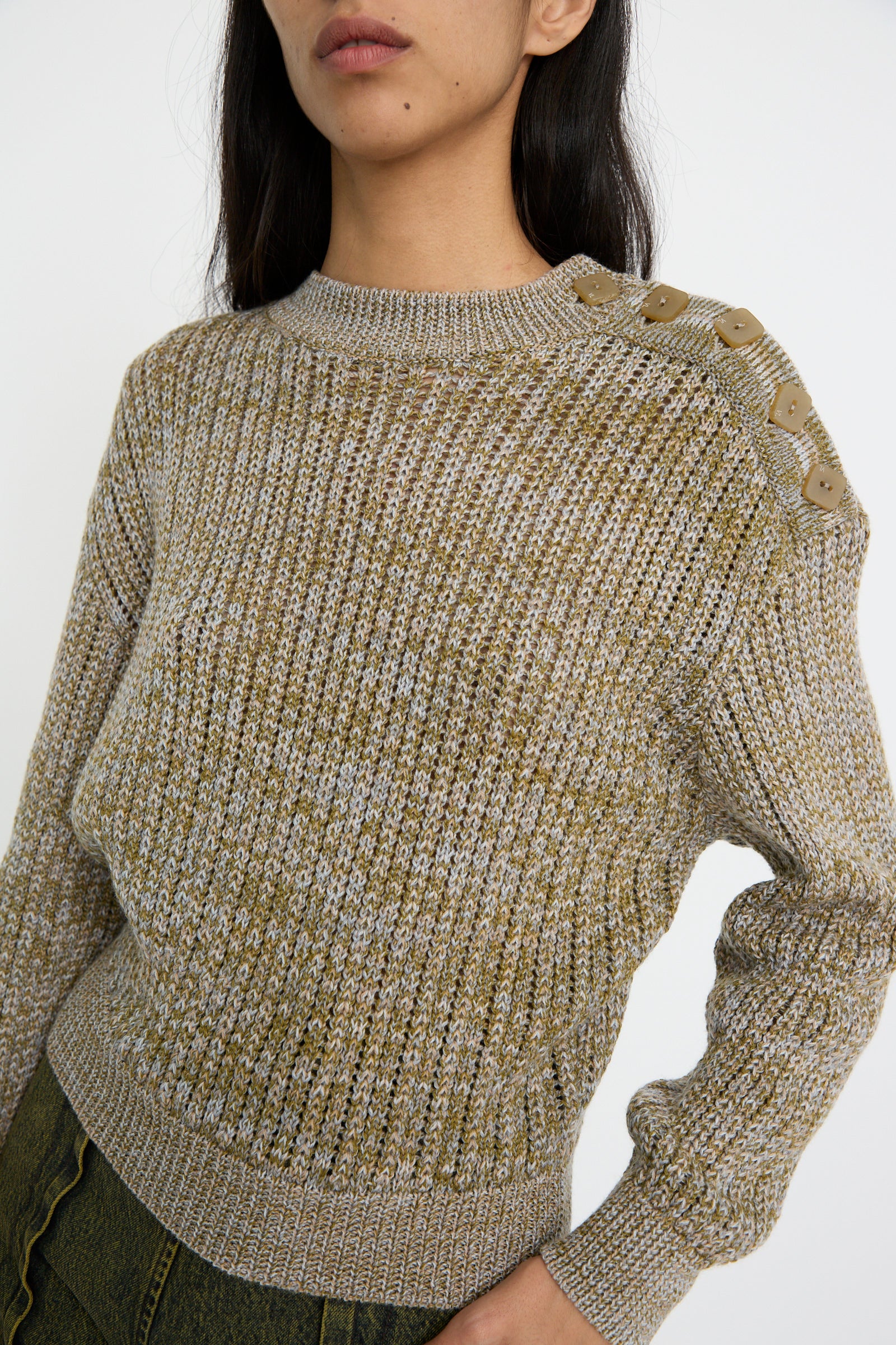 A person wearing the Veronique Leroy Button Shoulder Sweater in Meadown, styled with a boxy fit and button details on the shoulder, stands against a plain background.