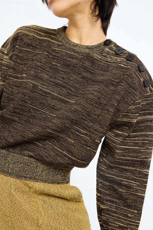 A close-up of a person wearing a Veronique Leroy Cotton Boxy Sweater in Pepper with shoulder button details.