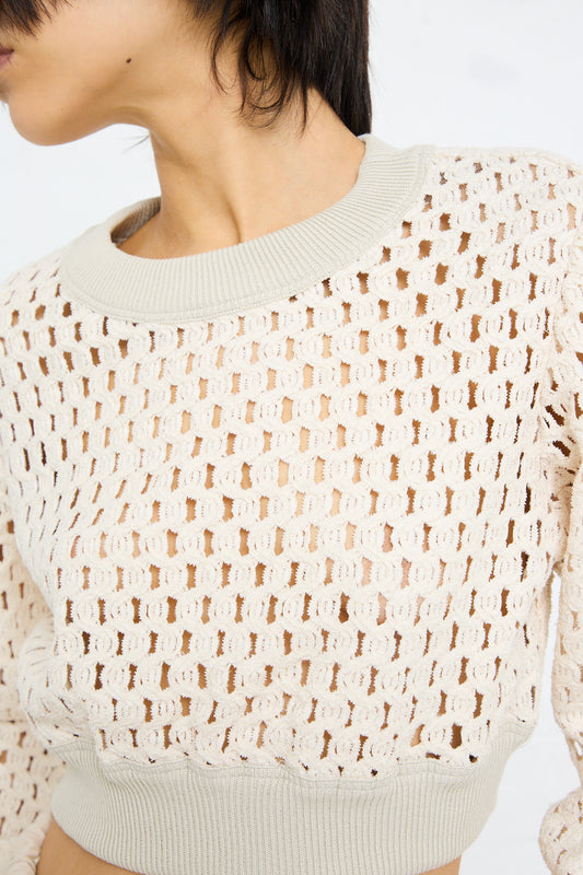 Close-up of a person wearing a Cotton Macro Mesh Cropped Sweater in Ivory by Veronique Leroy with a patterned design.