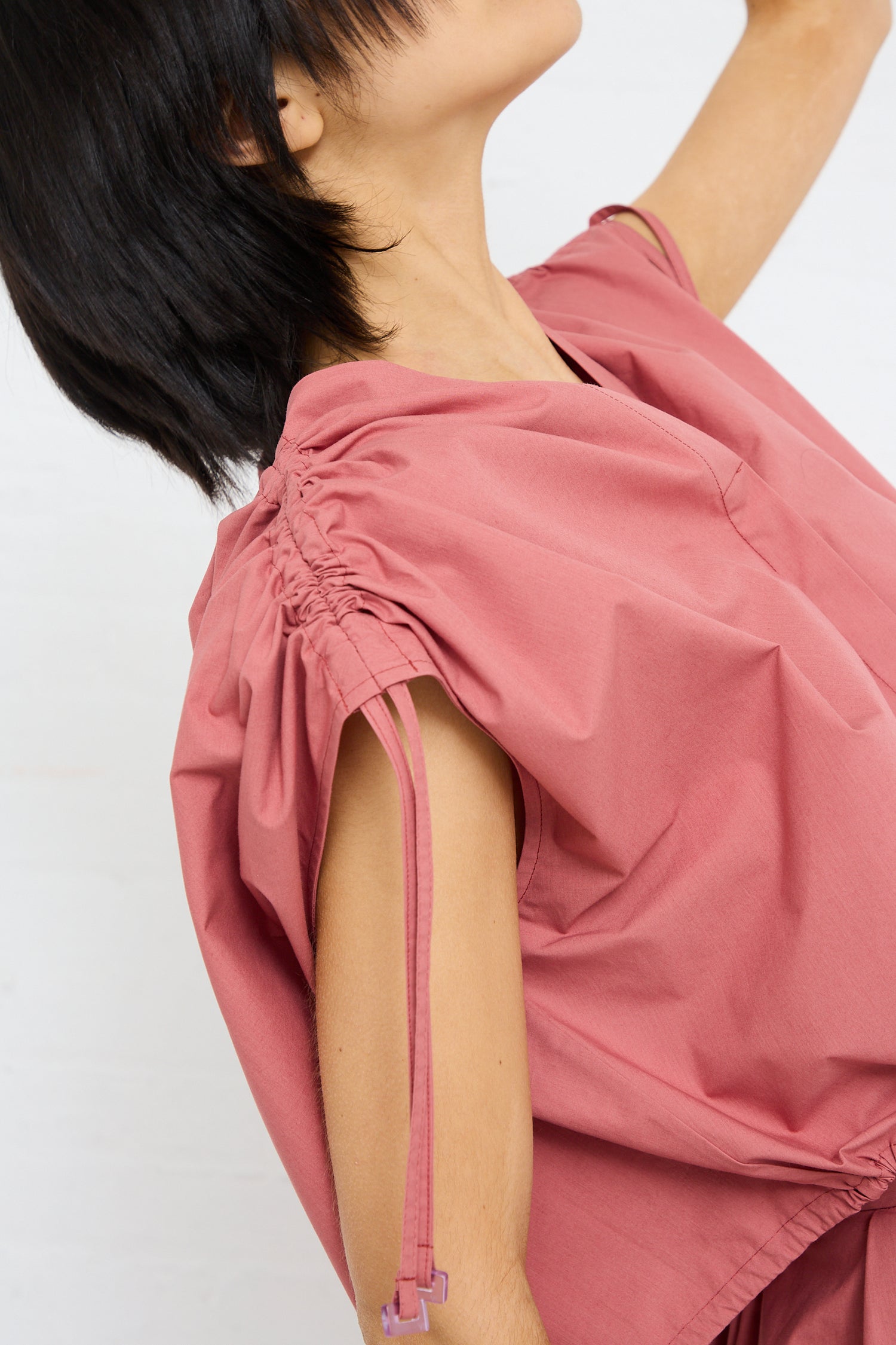 A person in a Cotton Poplin Gathered Top in Canyon by Veronique Leroy with adjustable ruche detail at the shoulder and a visible zipper.