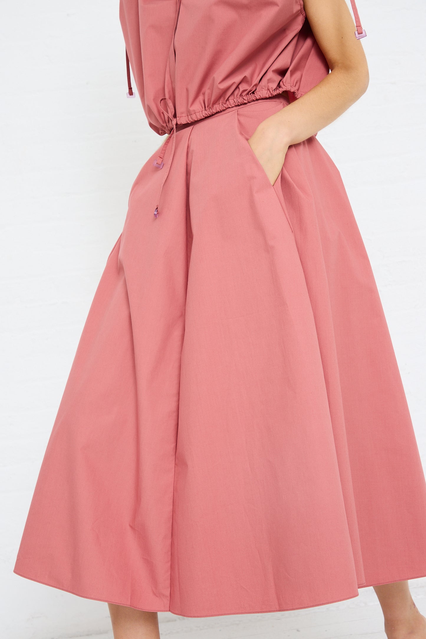 Woman showcasing the detail of a pink, wide-leg, pleated Cotton Poplin Skirt in Canyon by Veronique Leroy with her hand in the pocket.