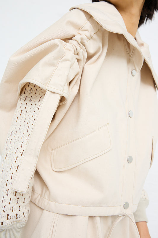 Close-up of a Veronique Leroy Denim High Neck Jacket in Chalk with a crochet sleeve detail and snap button closure.
