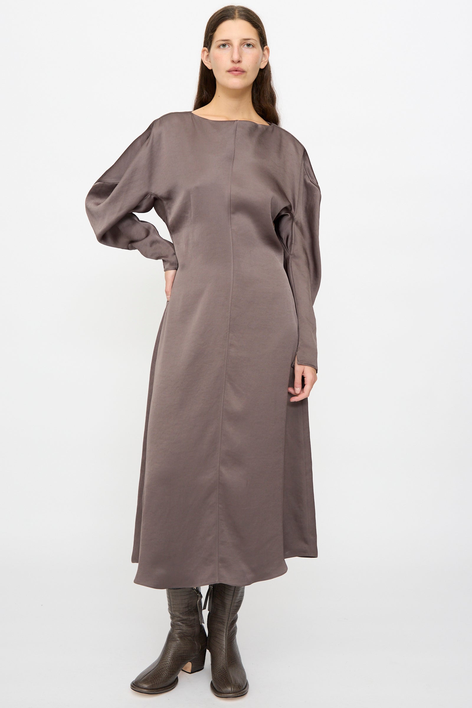 A woman stands against a plain background wearing the Veronique Leroy Dress with Scarf in Wood, styled with dark brown heeled boots.