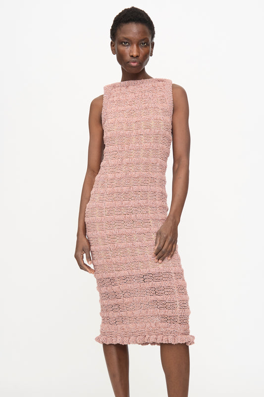 A person wearing the Veronique Leroy Smock Knit Dress in Dusk— a sleeveless, pink textured cotton-blend midi dress that falls below the knees—stands against a plain white background.