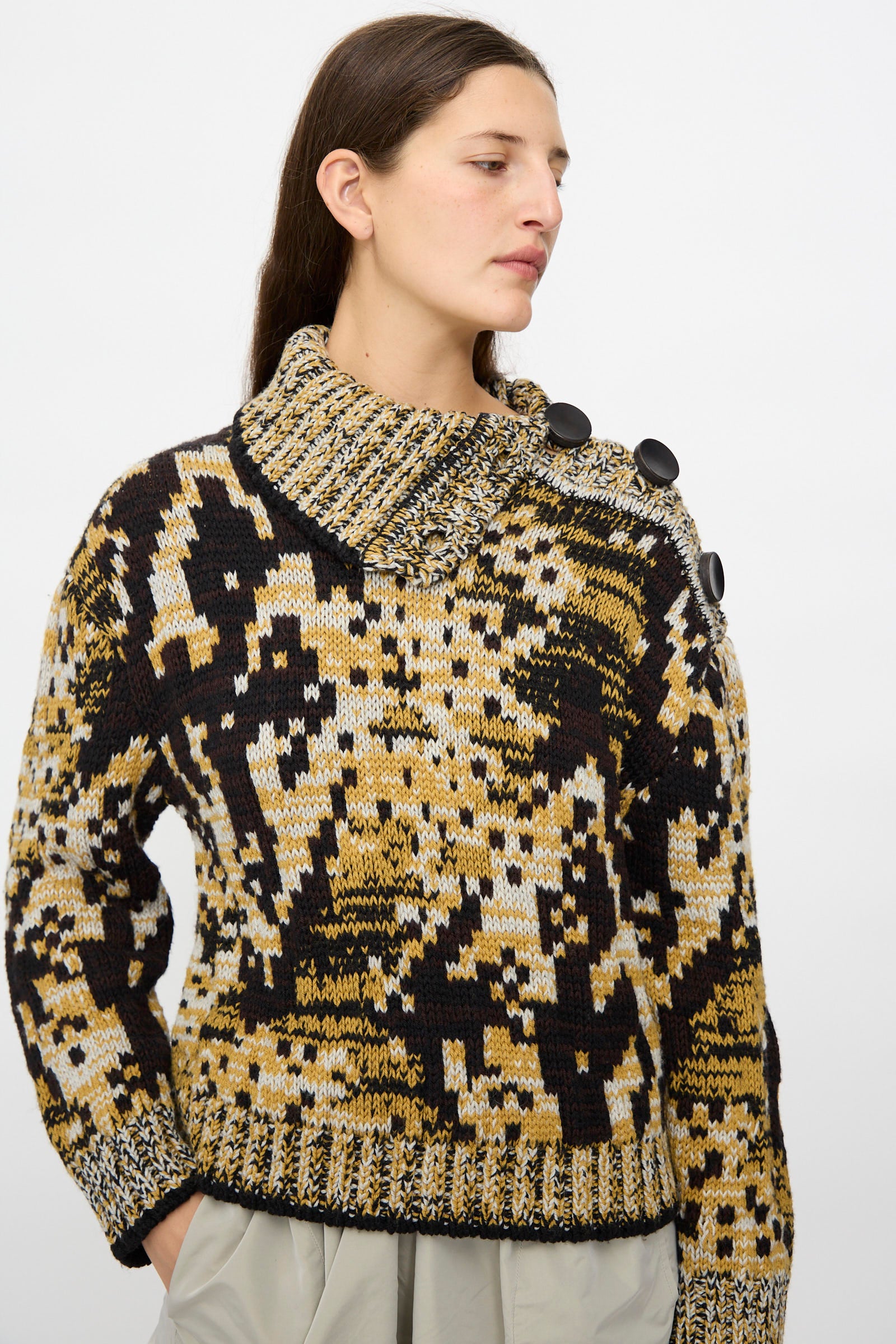 A person models the Veronique Leroy Sweater in Sepia—a relaxed fit, patterned knit with a high collar and large buttons—against a plain light background.