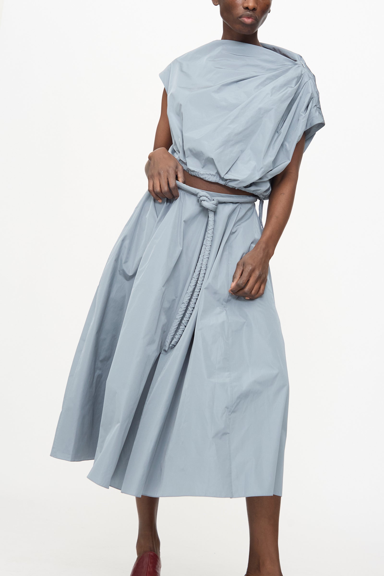 Model wears Veronique Leroy's Taffeta Skirt in Storm—a light blue, loose-fit two-piece with an adjustable rope belt and flowing A-line skirt—posed against a plain white background.