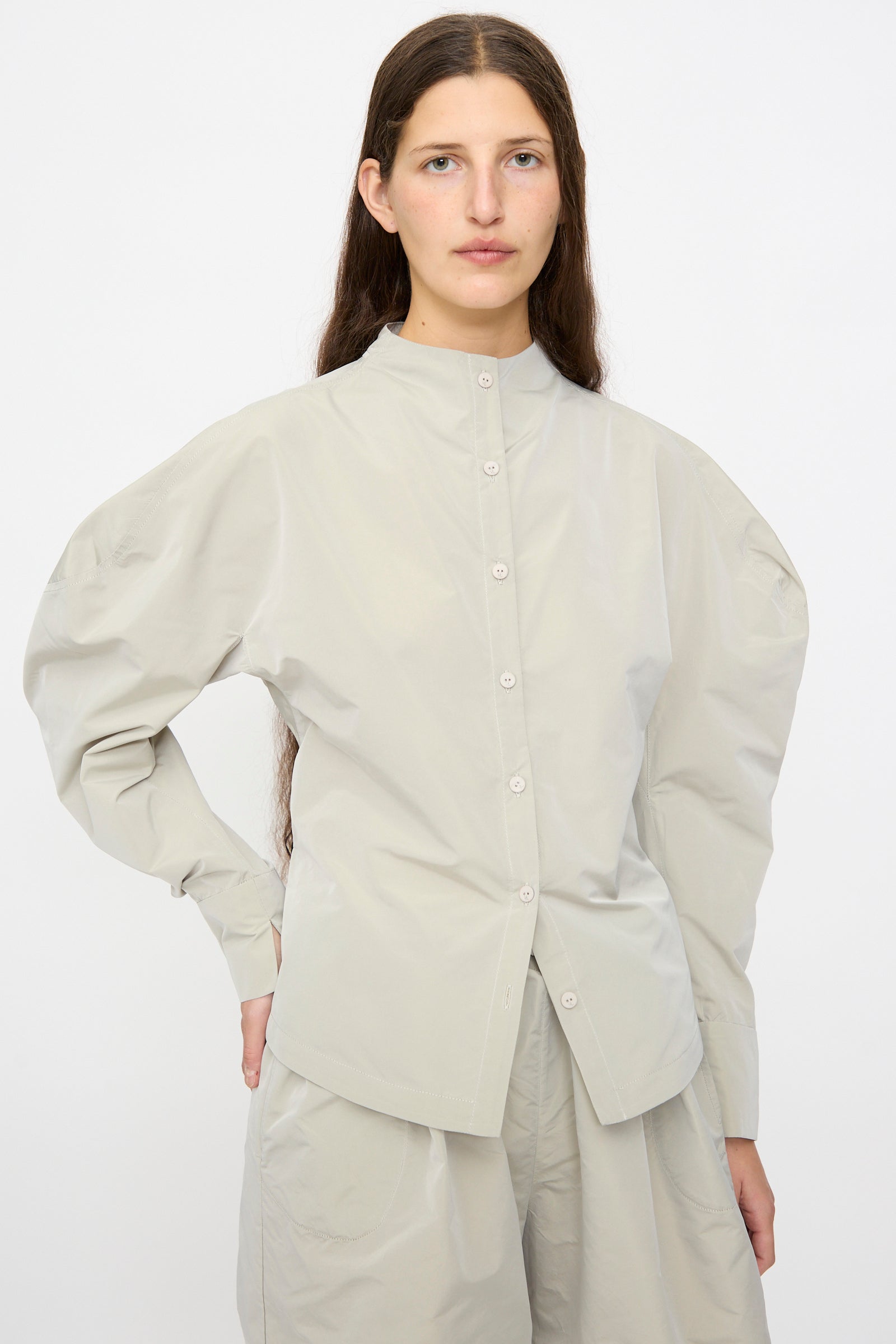 A person with long brown hair wears the Veronique Leroy Top with Scarf in Sage, standing against a plain white background.