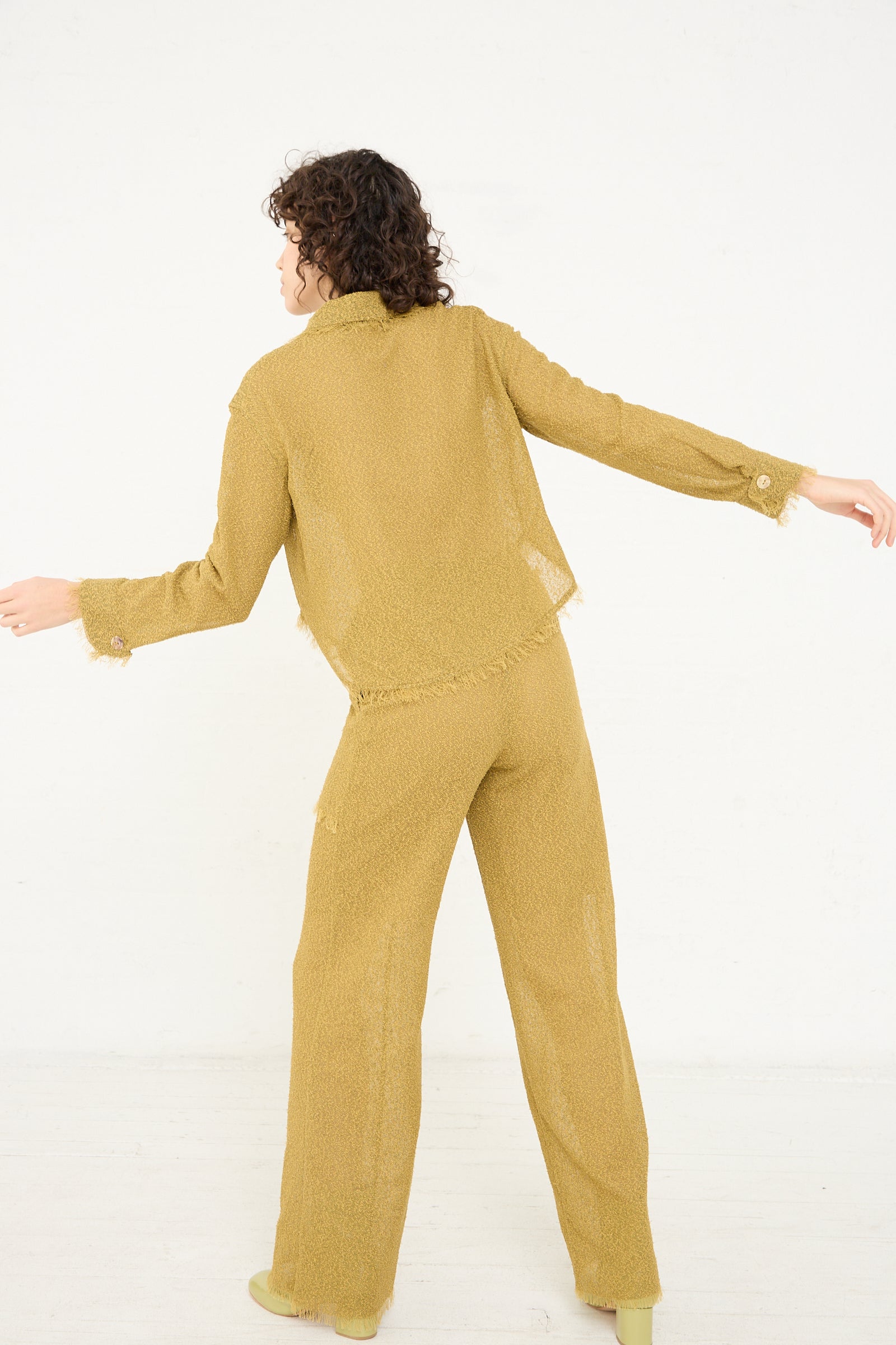 A woman is standing in a lightweight, yellow Tweed Blouse in Cumin by Veronique Leroy pajama set.