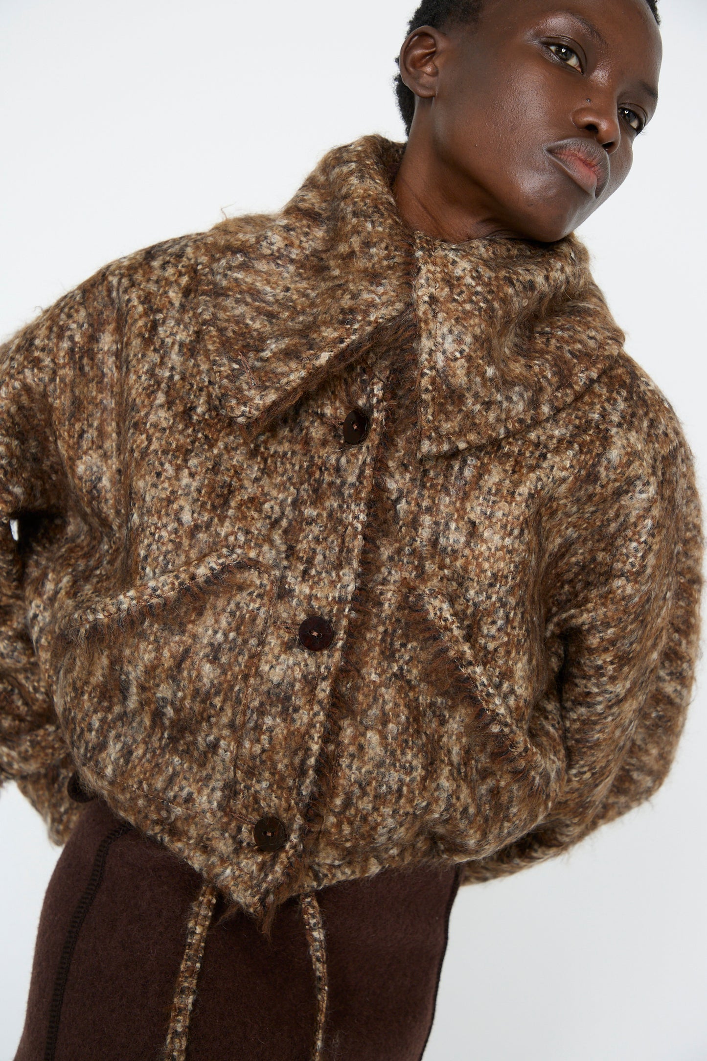 A woman in the Tweed Bomber Jacket in Bronzewood by Veronique Leroy, featuring an oversized collar, poses against a plain background.