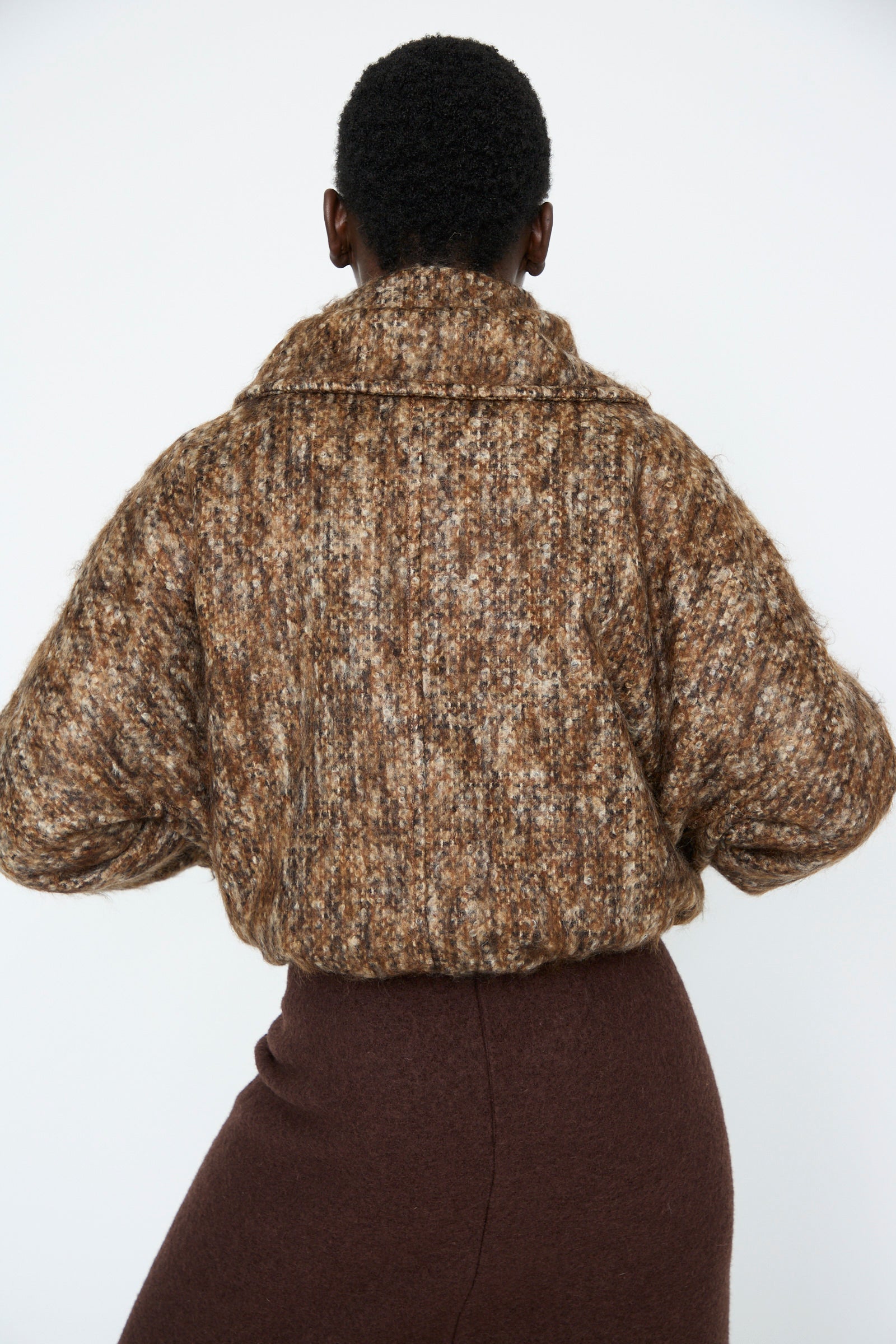 A person is pictured from behind, wearing a Bronzewood Tweed Bomber Jacket by Veronique Leroy and a brown skirt against a plain background.