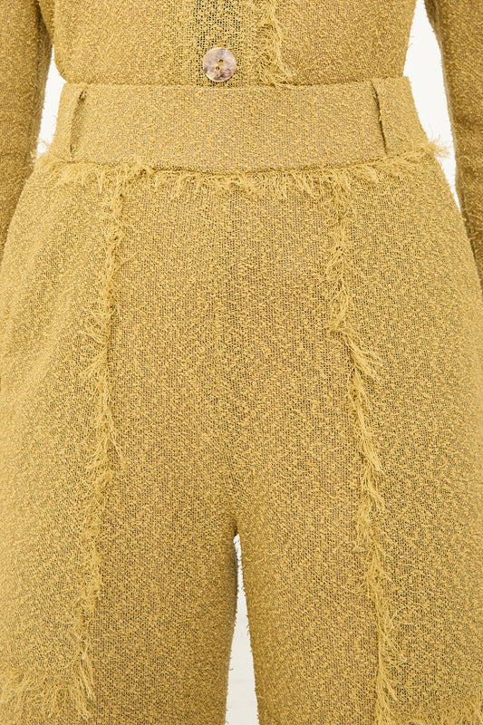 The back view of a woman wearing a Veronique Leroy yellow fringed, high-waisted jumpsuit with oversized patch pockets.