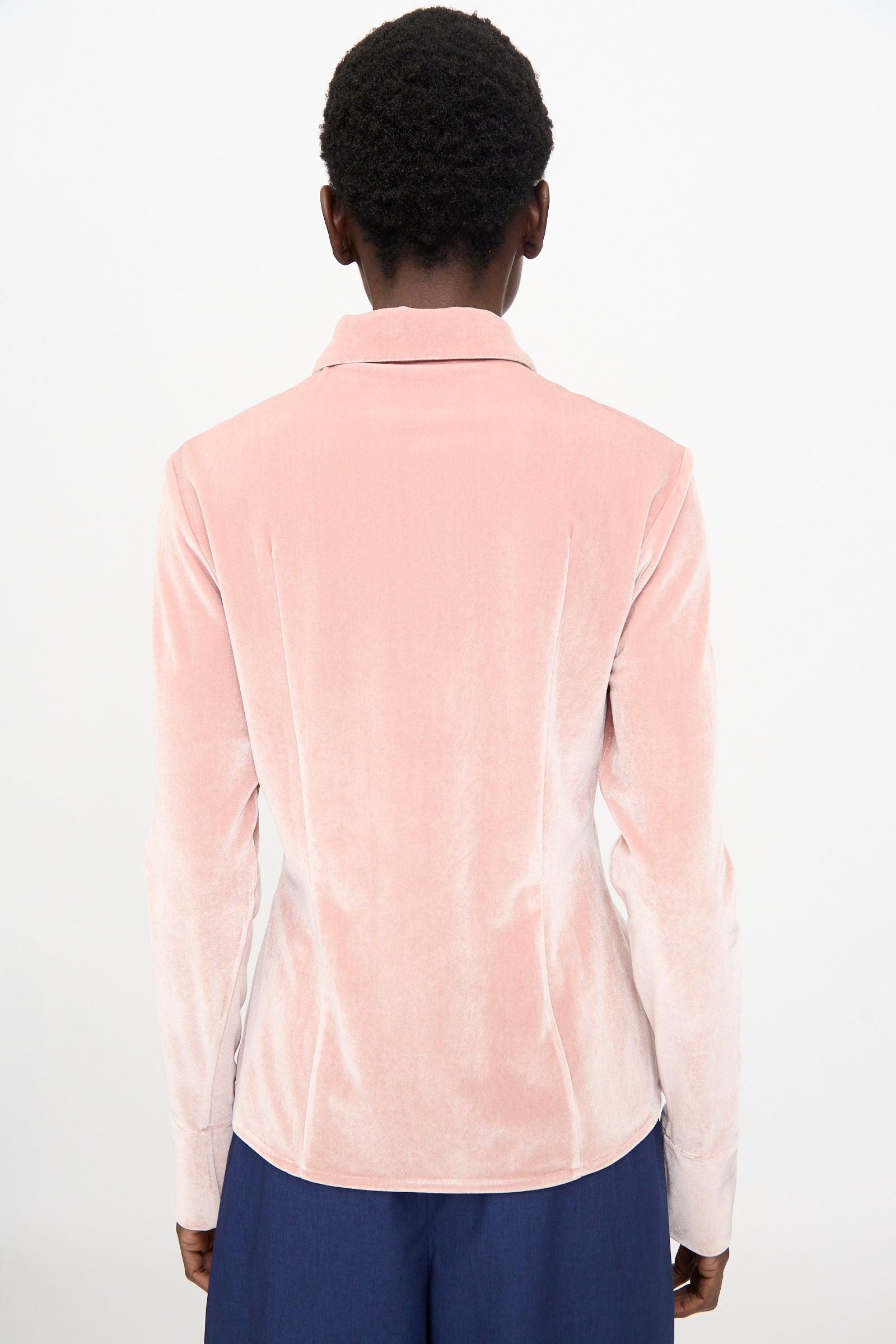 A person faces away from the camera, wearing the Veronique Leroy Velvet Classic Shirt in Blush with long sleeves and dark blue pants, set against a plain white background.