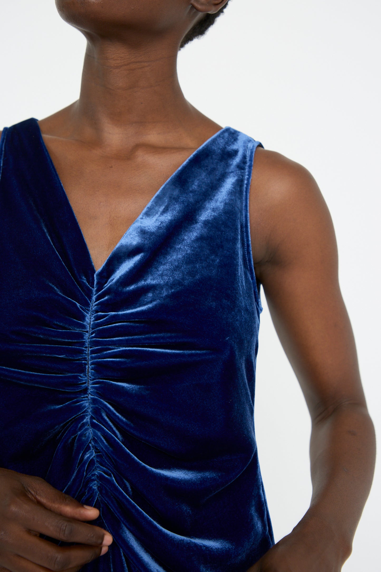 A woman dressed in the Velvet Gather Front Dress in Cobalt by Veronique Leroy, featuring the v-neckline, while standing against a plain background.