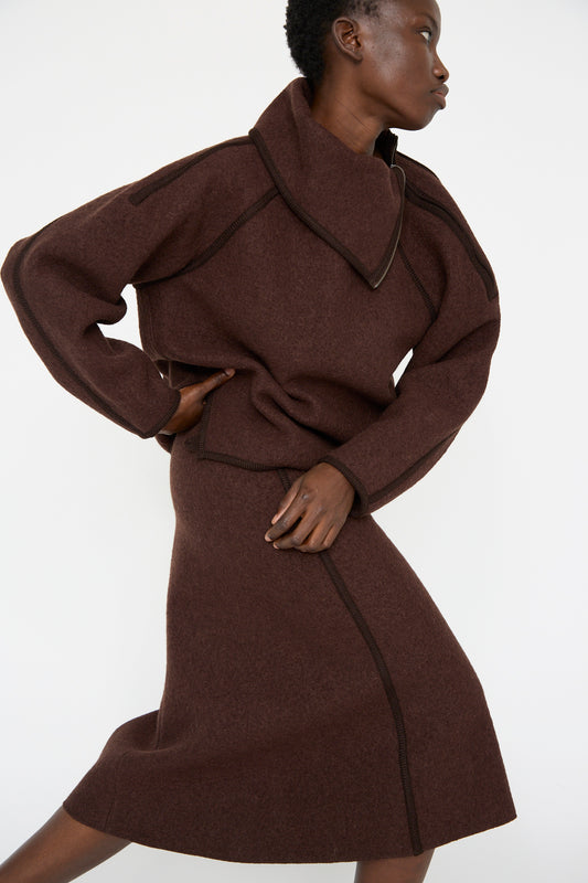 A person wearing a Veronique Leroy Wool Long Skirt in Choco and a brown sweater poses against a plain, light background.