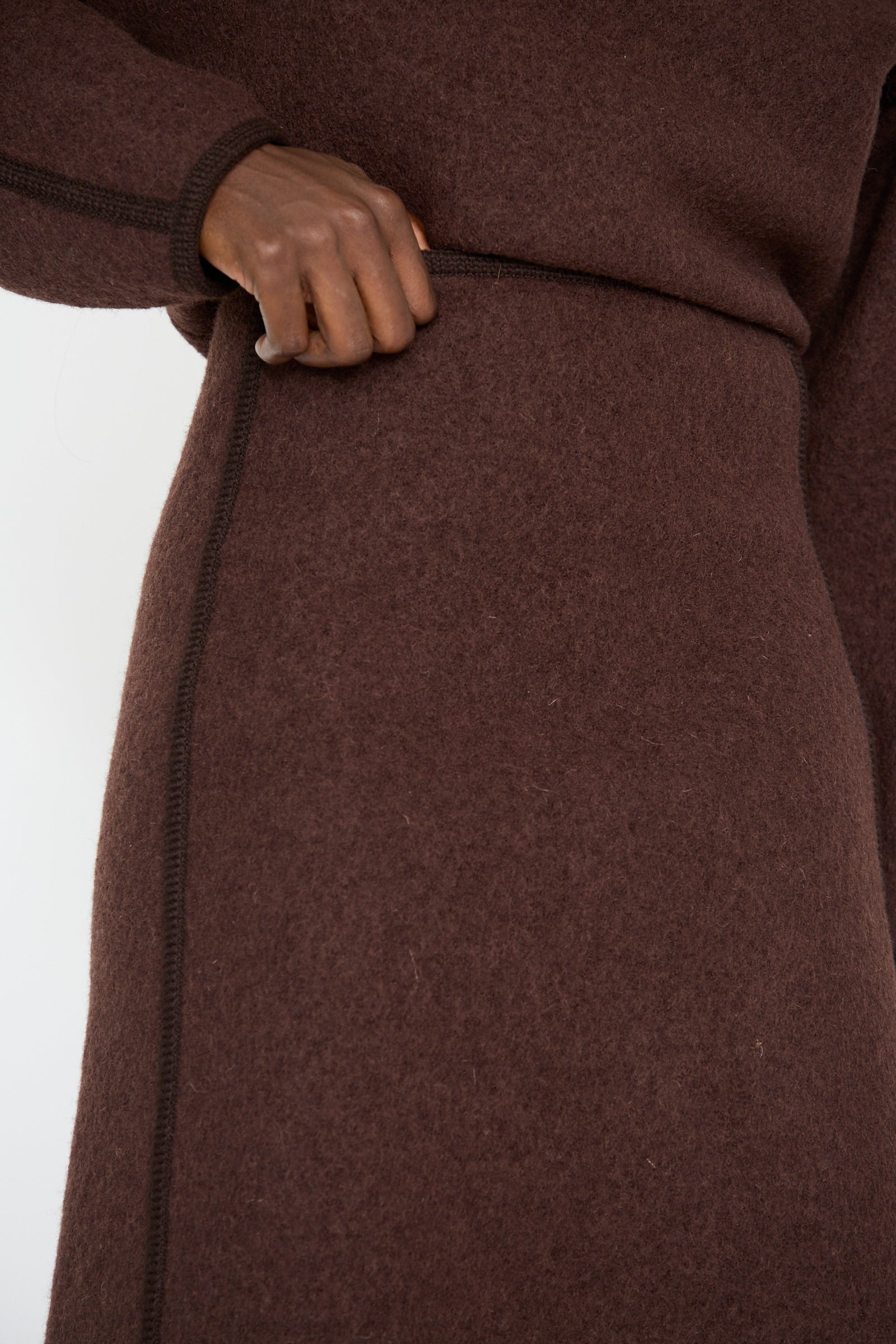 Close-up of a person wearing Veronique Leroy's Wool Long Skirt in Choco, with their hand resting on the waistband.