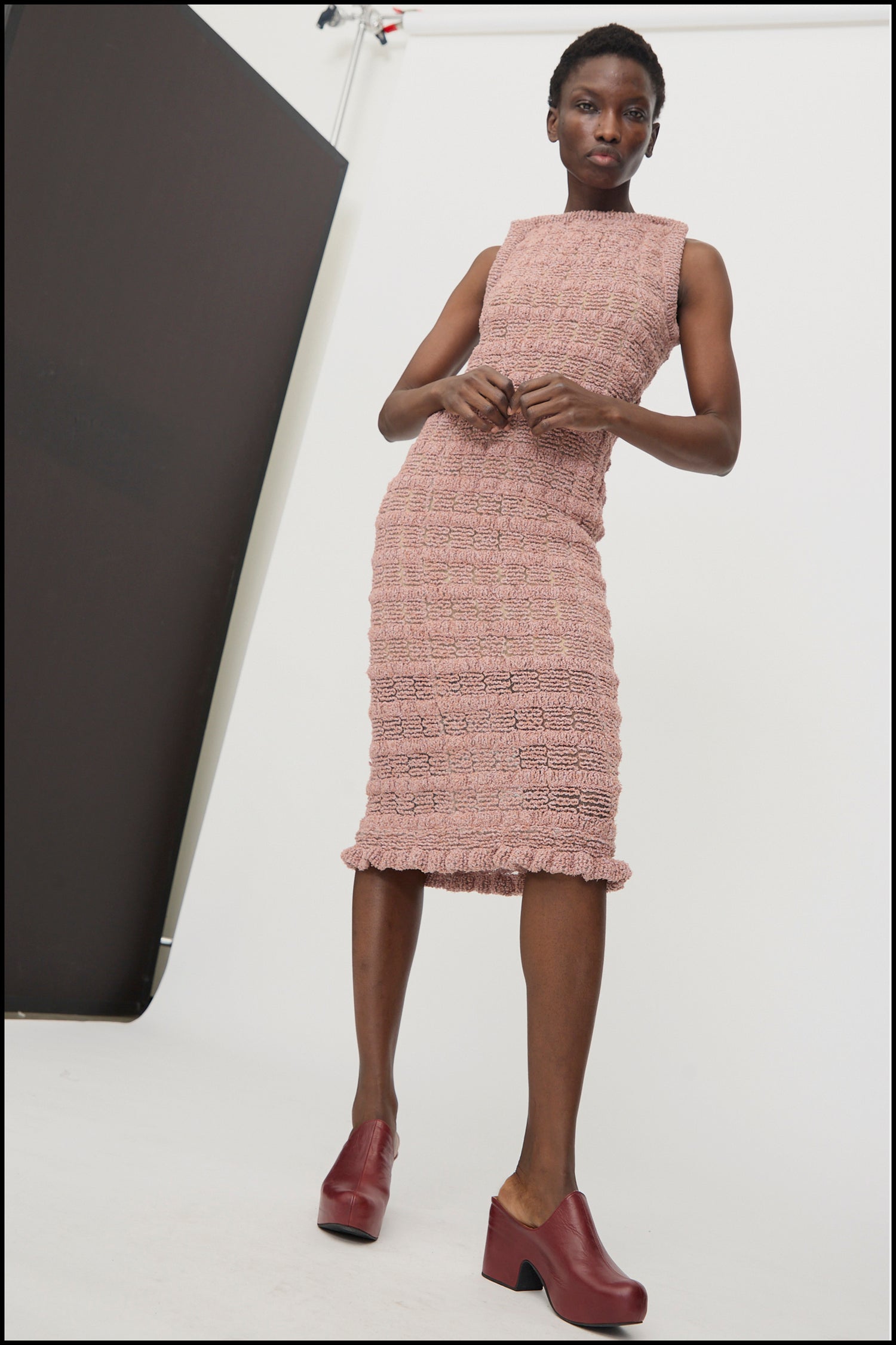 A woman standing against a white background wearing Veronique Leroy's Smock Knit Dress in Dusk.