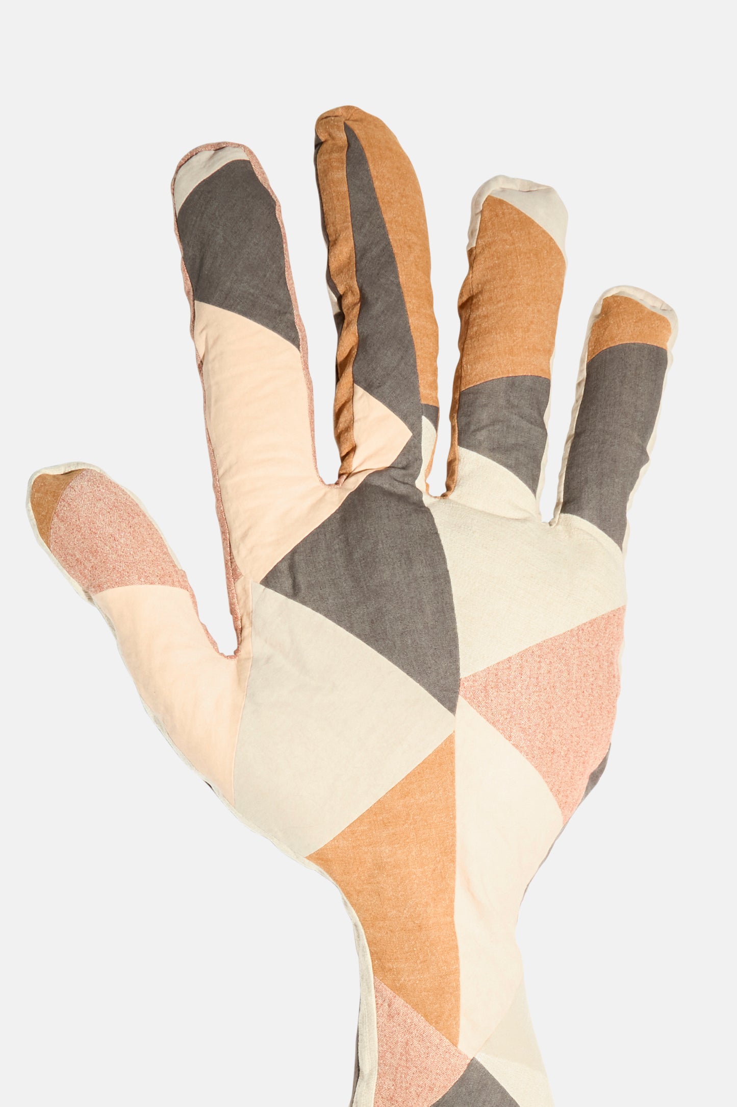 The Wiener Times Sonia Delaunay Tissu Simultané Giant Hand Bolster I is a hand-shaped pillow with a geometric patchwork in beige, pink, brown, and gray, inspired by Wiener Werkstätte design and shown on a plain white background.