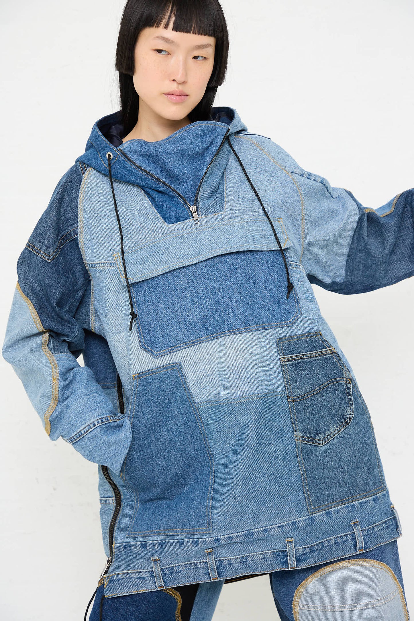 A person wearing the Anorak in Blue from WildRootz, a color-block denim pullover handmade from recycled denim, poses against a white background.