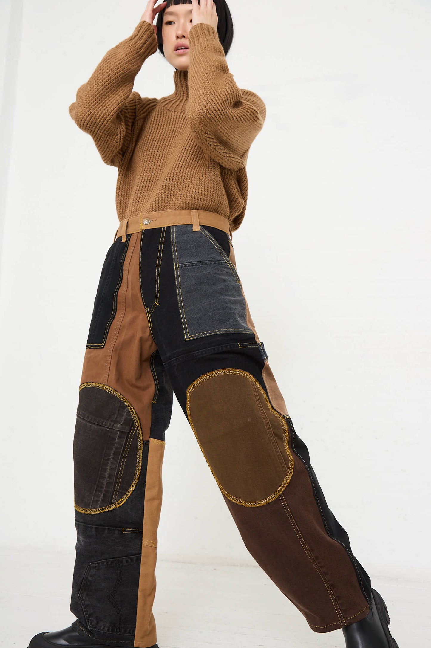 Person posing in a brown knit sweater and Reworked Jeans in Black and Brown I by WildRootz, with hands touching their head, against a plain white background.