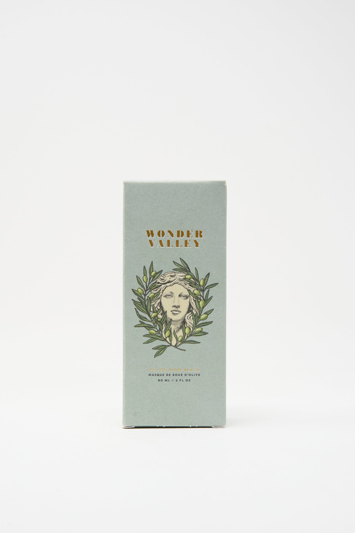 A rectangular box of Wonder Valley Olive Mud Mask, showing an illustrated face with olive branches on a light green background, stands upright on a white surface; hydrates and balances skin with an elegant touch.