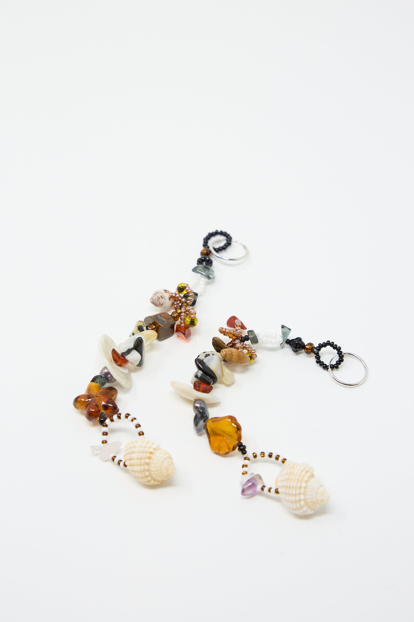 Two keychains featuring assorted natural stones, glass beads, and shells arranged in a line on a plain white background evoke the elegant style of Yona Kohen’s Coquina Earrings.