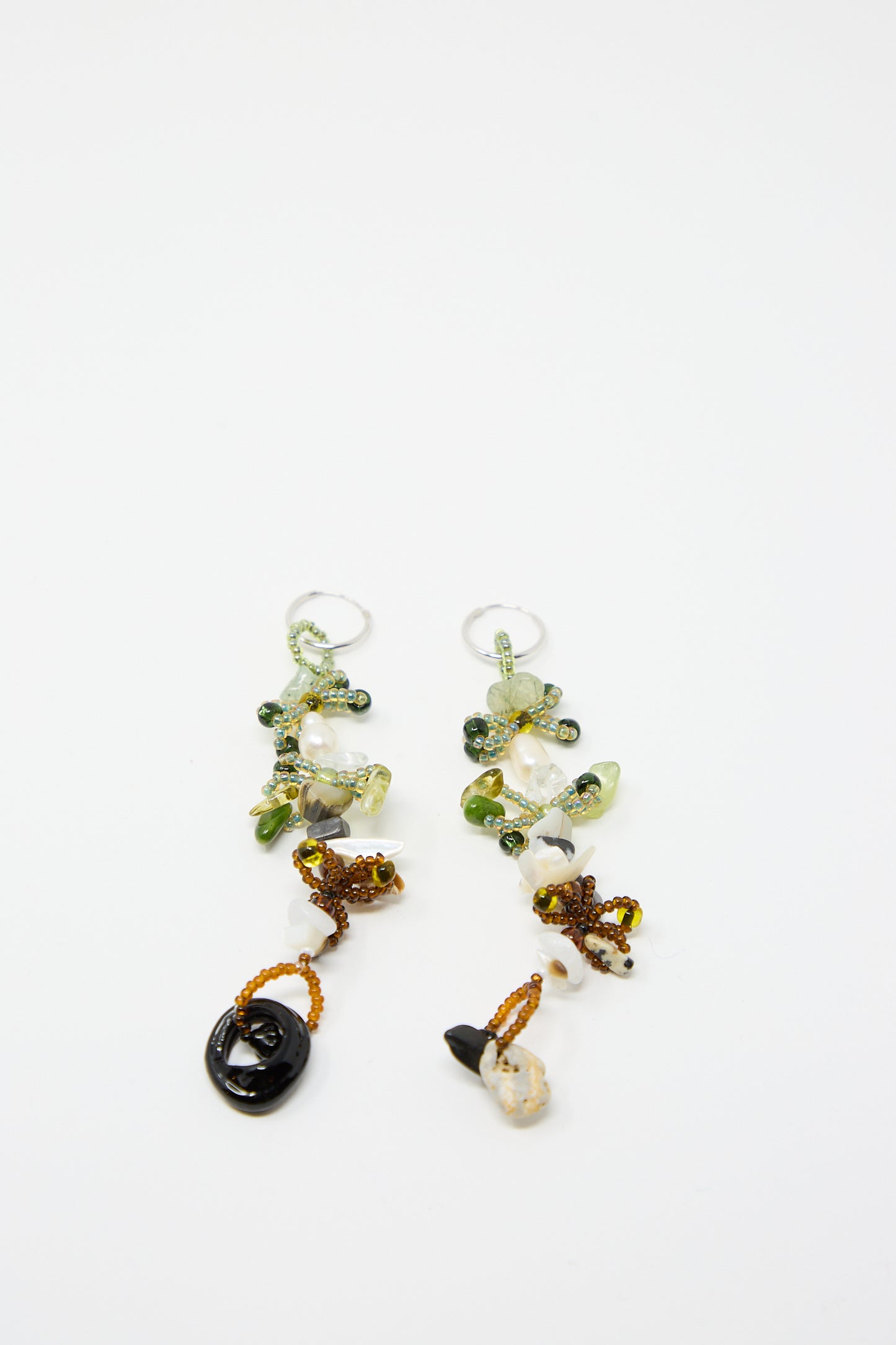 Introducing the Harvest Earrings 2.0 by Yona Kohen: a beautiful pair of hand-beaded dangle earrings crafted with green, brown, and clear glass beads set against a delicate light background.