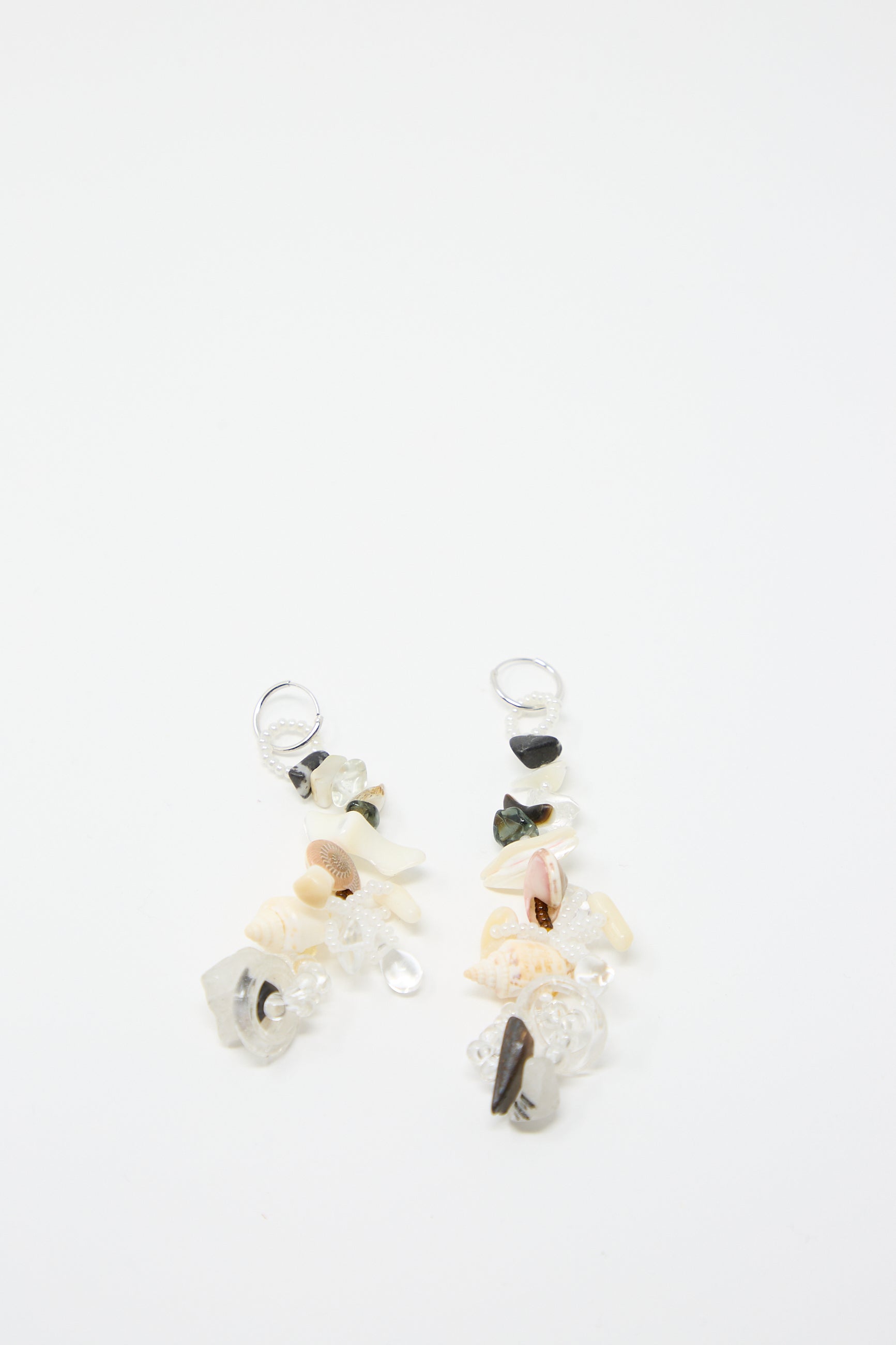 Introducing the Swamp Earrings by Yona Kohen - a pair of hand-beaded earrings adorned with an eclectic mix of small stones, glass beads, and shells set against a white background.