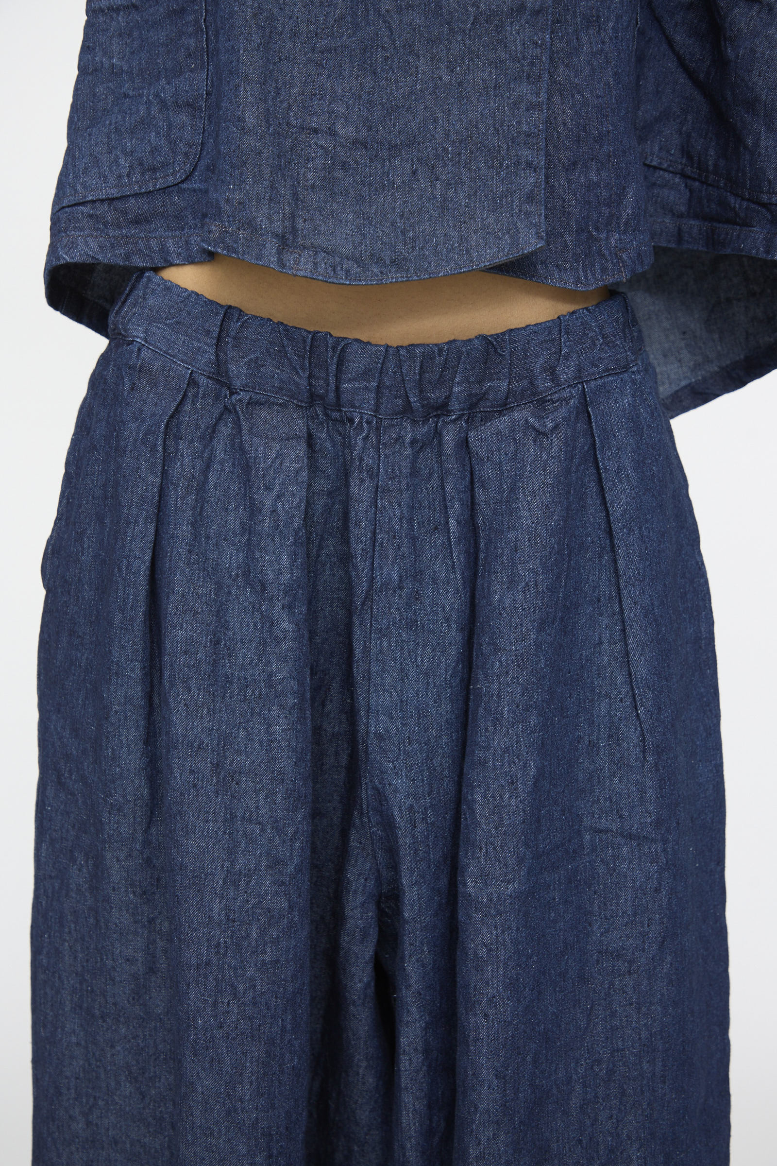 Close-up of a person wearing nest Robe’s 10.oz Linen Denim Wide Tapered Trousers in Indigo Blue, showing the waistband and styled with a matching cropped top.