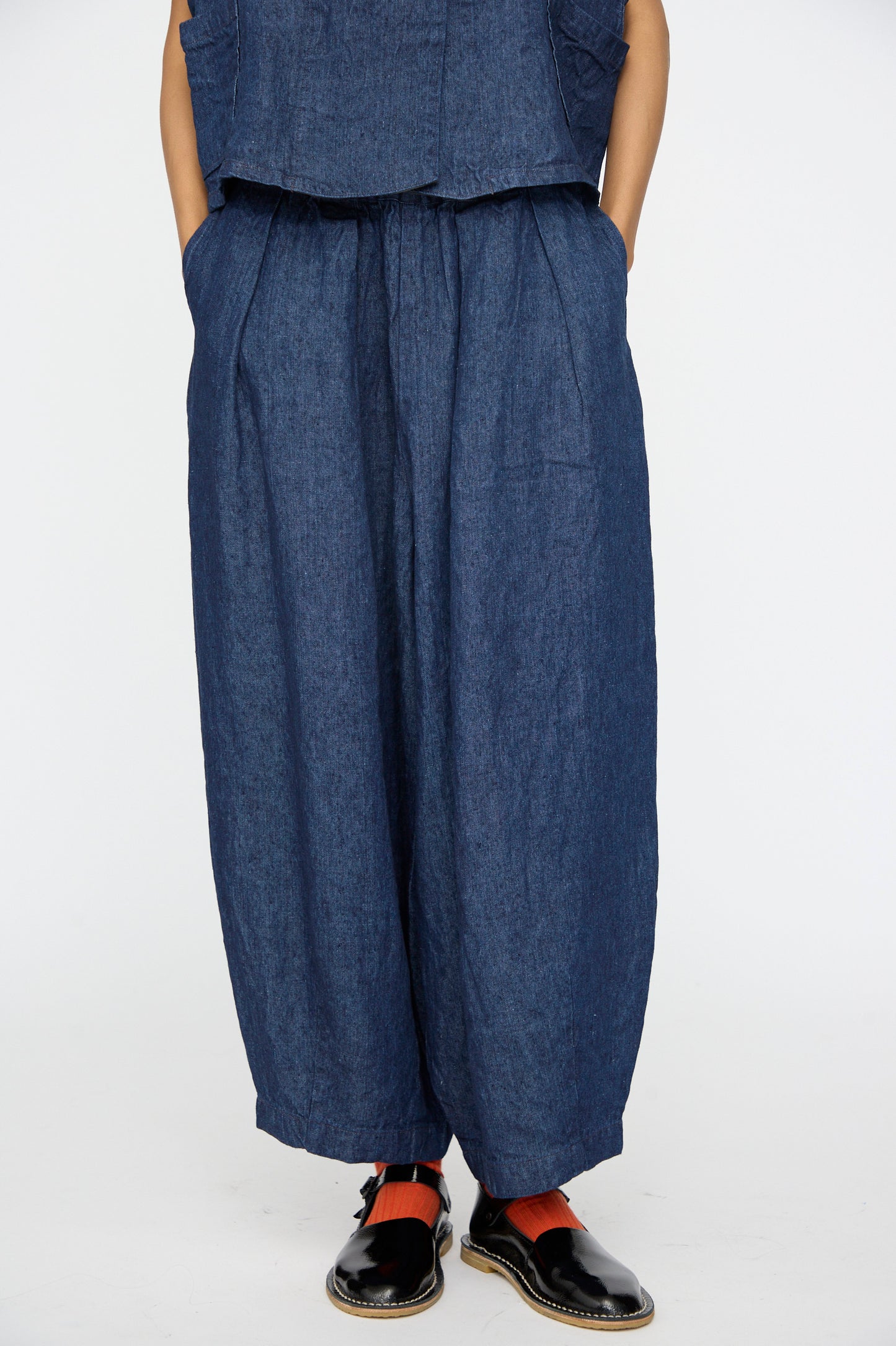 A person wears nest Robe's 10oz Linen Denim Wide Tapered Trousers in Indigo Blue, paired with a matching top and black shoes with red straps, standing against a white background for an effortlessly stylish look.
