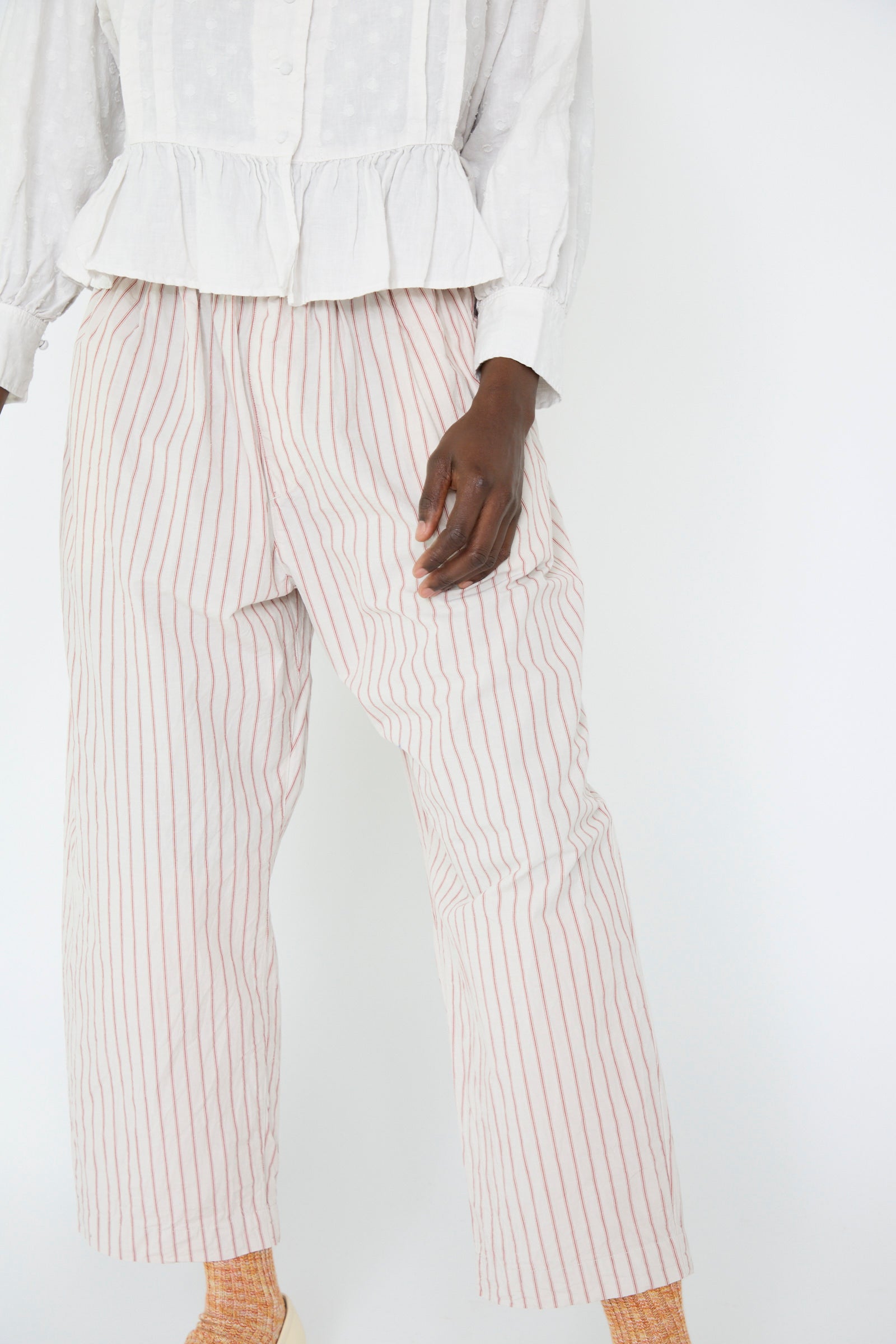 A person dressed in a white blouse and nest Robe's Cotton Linen Easy Pants in Stripe stands against a plain white background.