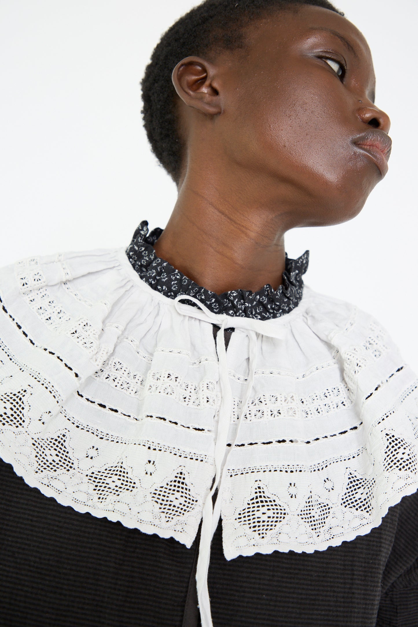 A woman wears the nest Robe Linen Cotton Lace Detachable Collar in Off White, and gazes to the side against a simple backdrop.