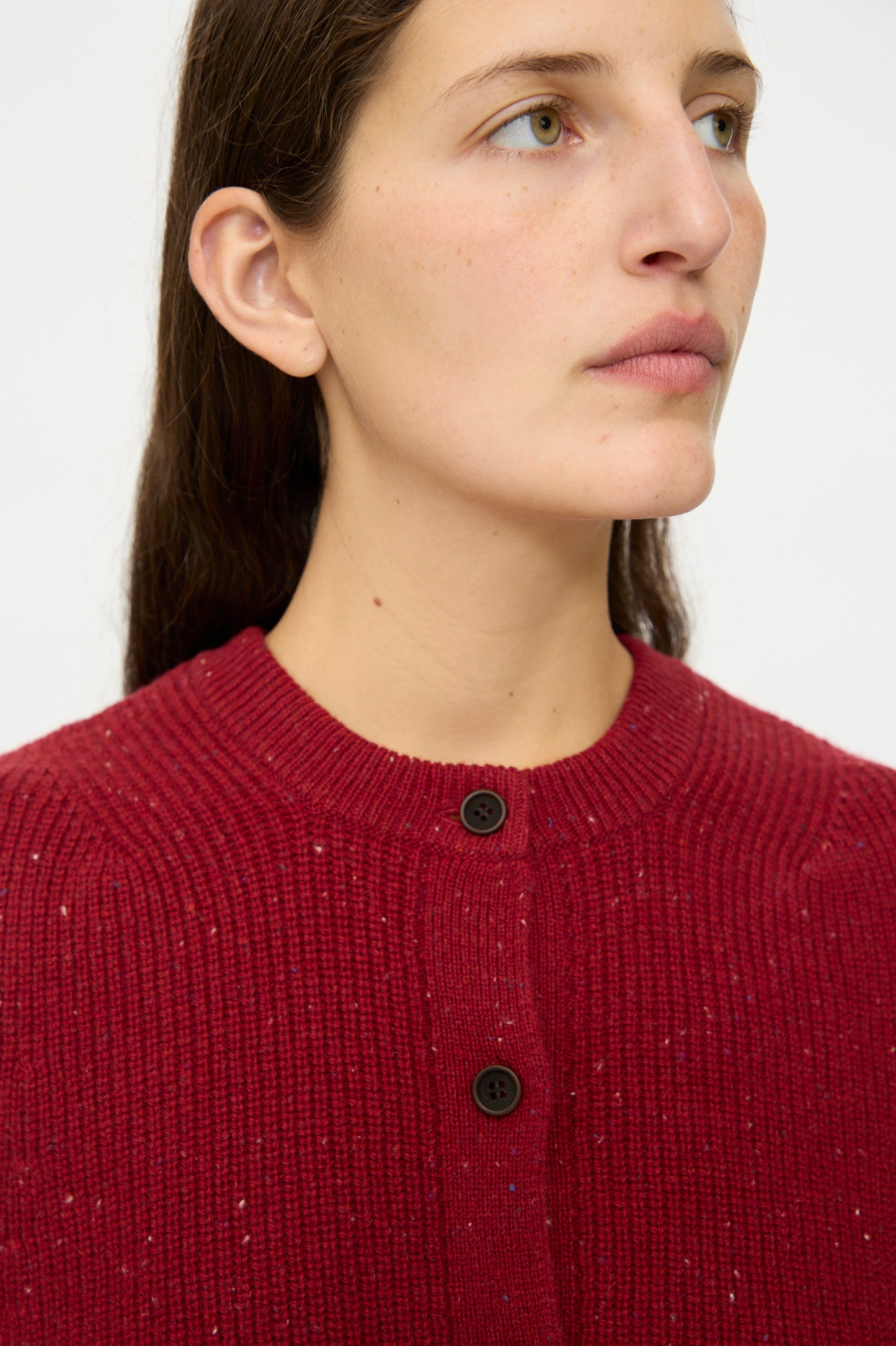 A person with long brown hair wears the nest Robe Rib Knit Buttoned Vest in Wine. The background is plain white.