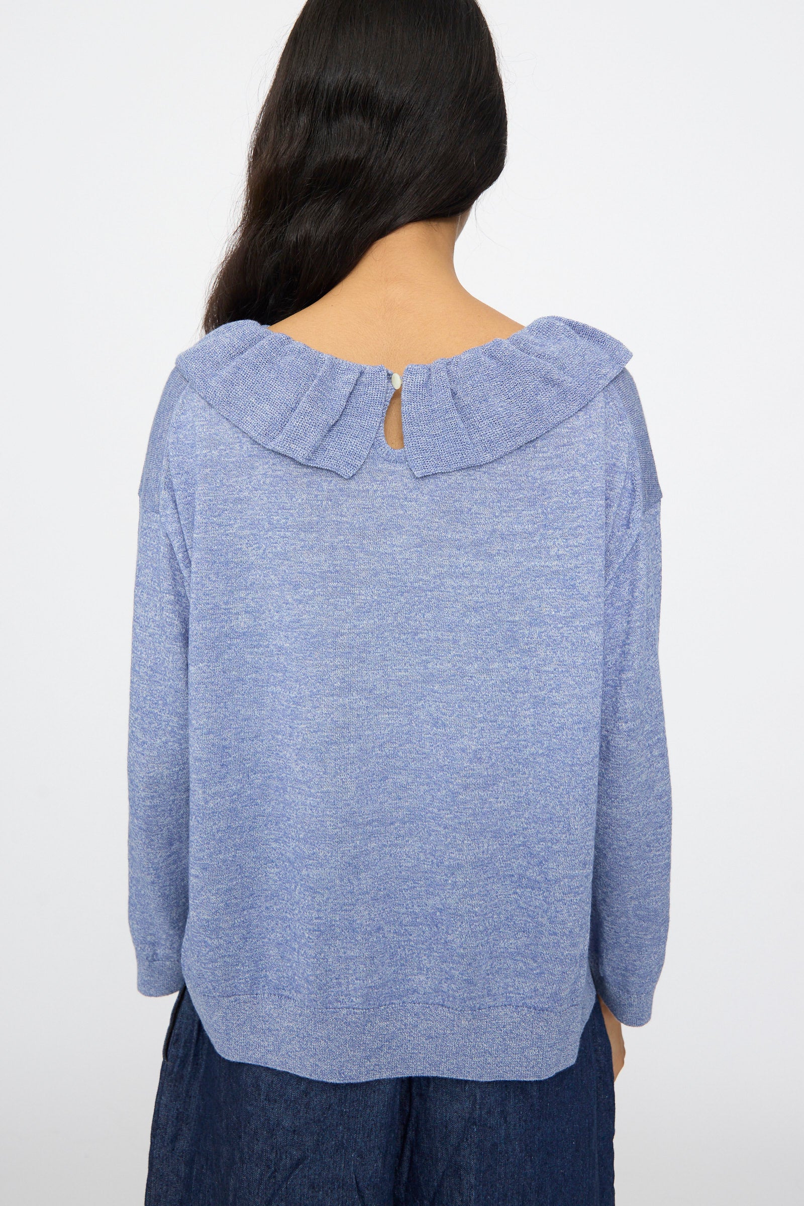A person with long dark hair is seen from the back wearing the nest Robe Ruffle Collar Knit Pullover in Blue, set against a plain white background.