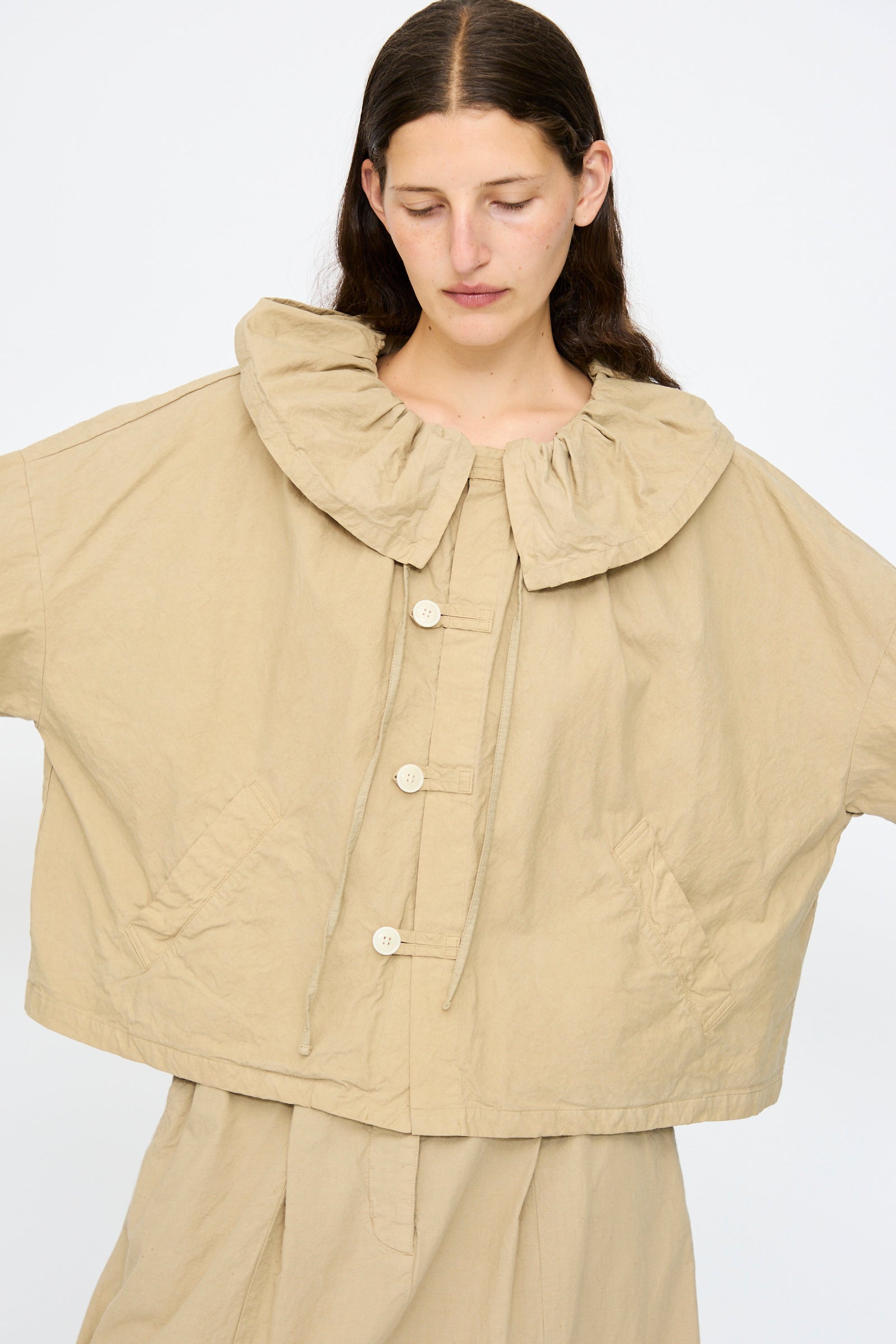 A person wearing the nest Robe Super Water-Repellent Supima Cotton Leaf Collar Jacket in beige, styled with a matching skirt.