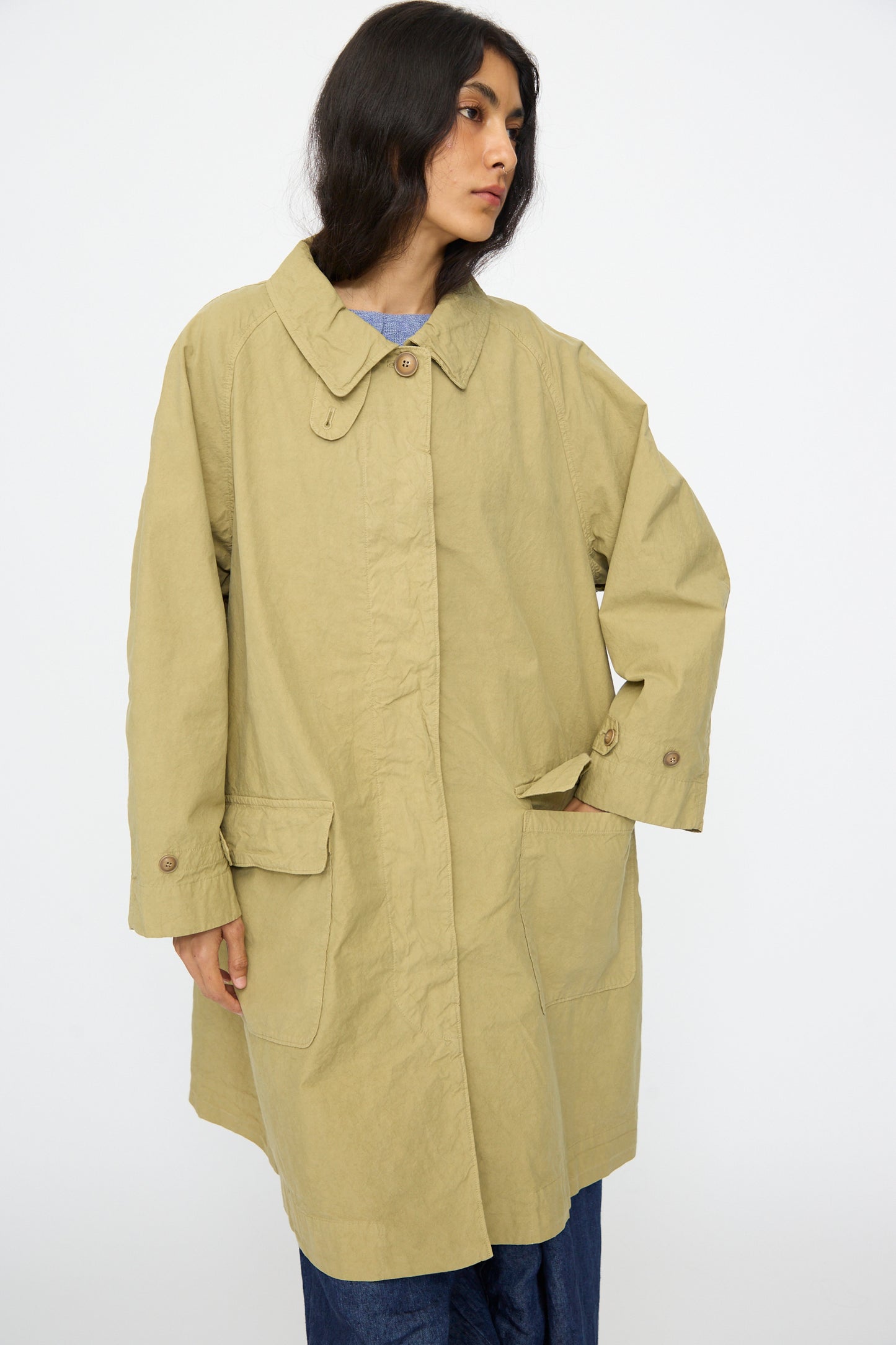 A person wearing the nest Robe Supima Cotton Topcoat in green, featuring a loose fit and large front pockets, stands against a plain white background.