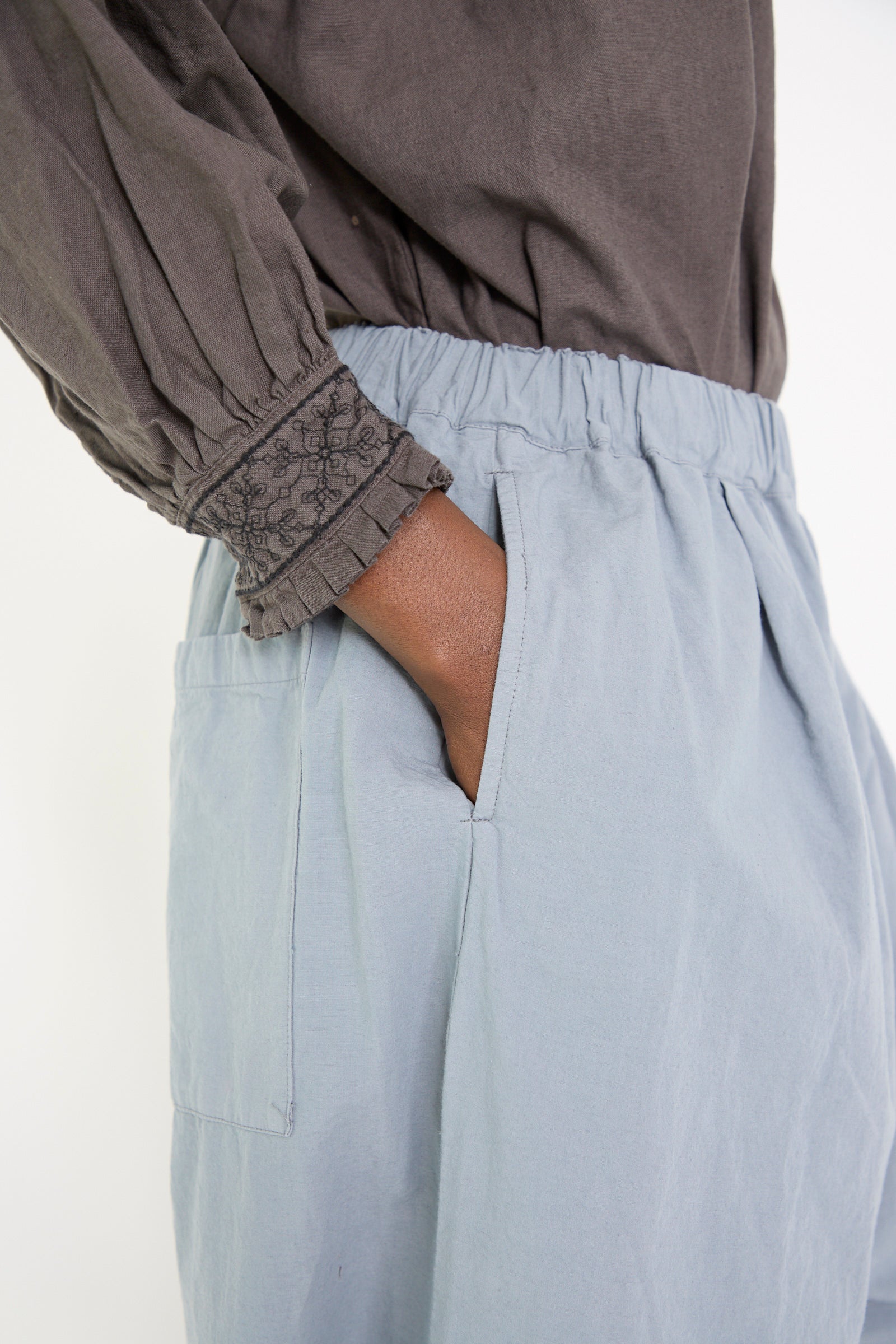 A woman wearing a dark long-sleeve shirt and the Water Repellent Cotton Linen Omi-Zarahi Wide Pant in Blue by nest Robe, with one hand in the pocket, side view.