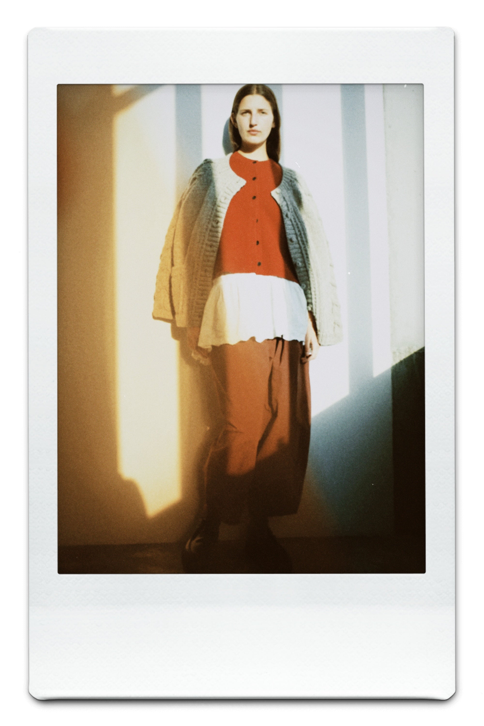 A polaroid photo of a person wearing pieces from nest Robe's FW25 collection with a orange filter.