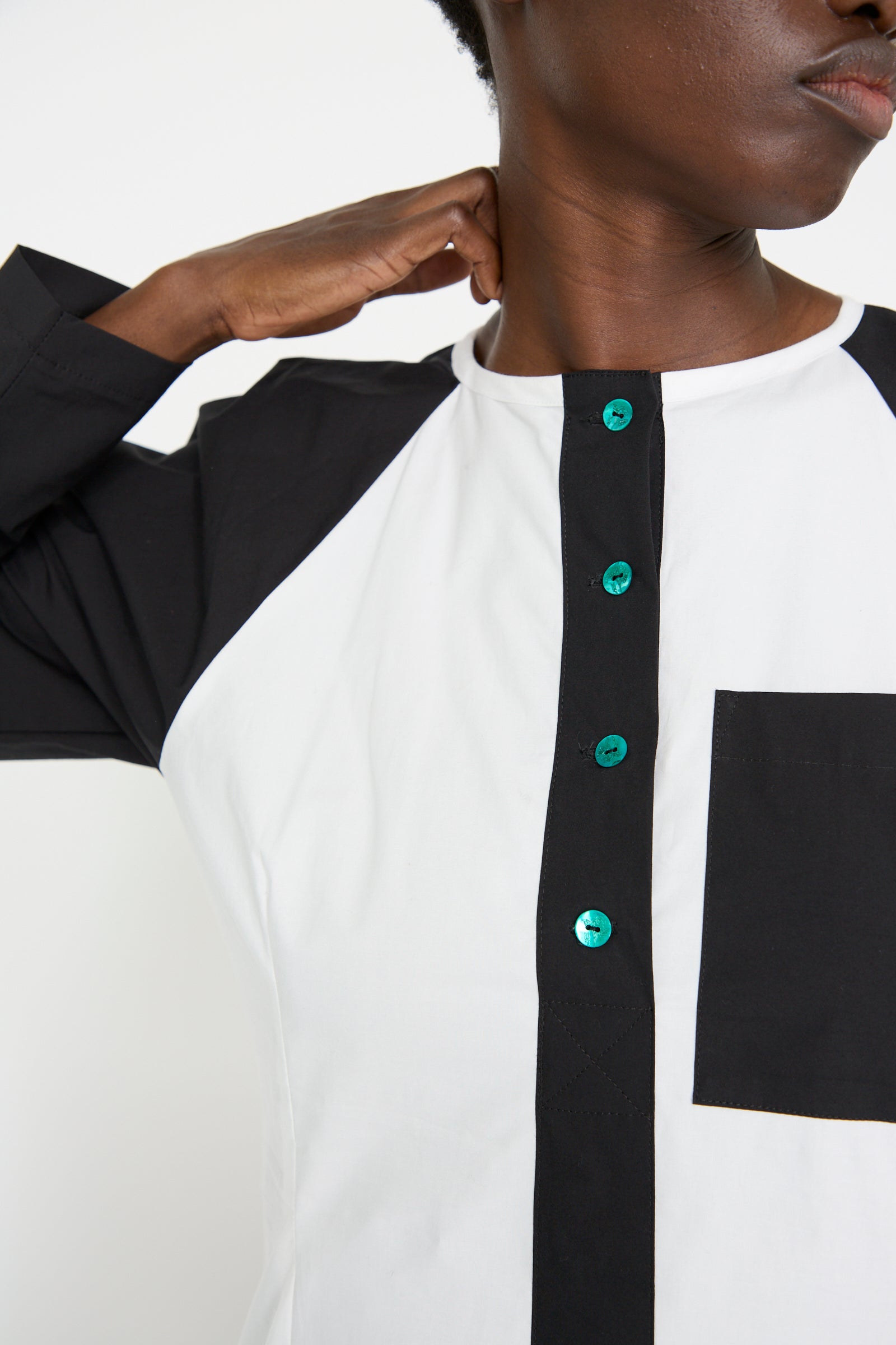 A close up of a woman wearing the Cotton Poplin Frame Dress in Flash by SC103, adjusts her collar.