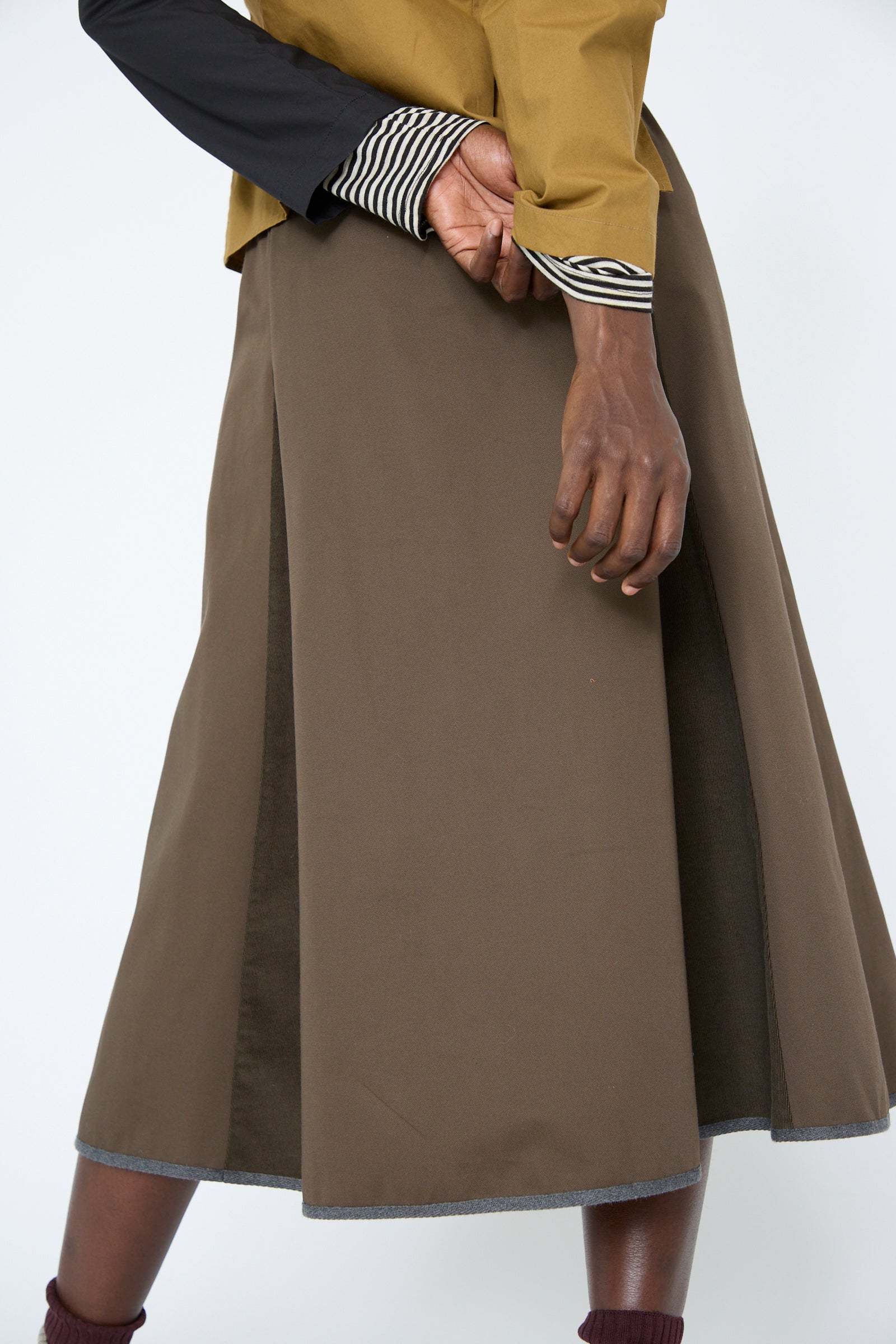 A woman wearing the SC103 Cotton Twill Axis Skirt poses with one hand holding the other behind her back.