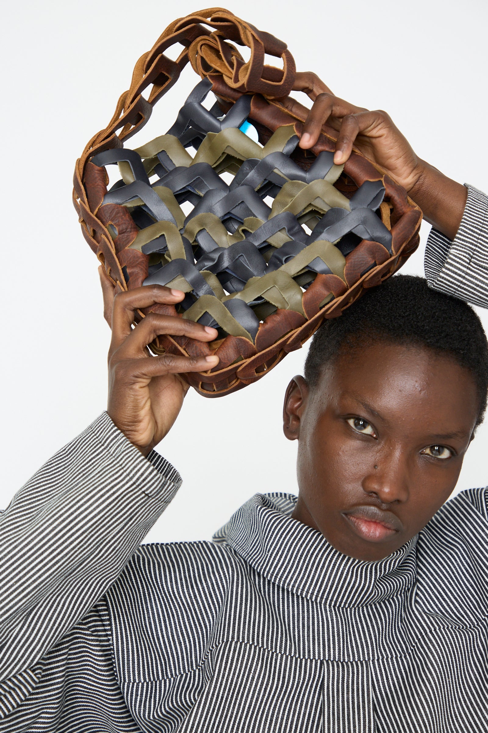 A woman in a striped outfit lifts the SC103 Leather Links Tote in Anise with Green above their head.