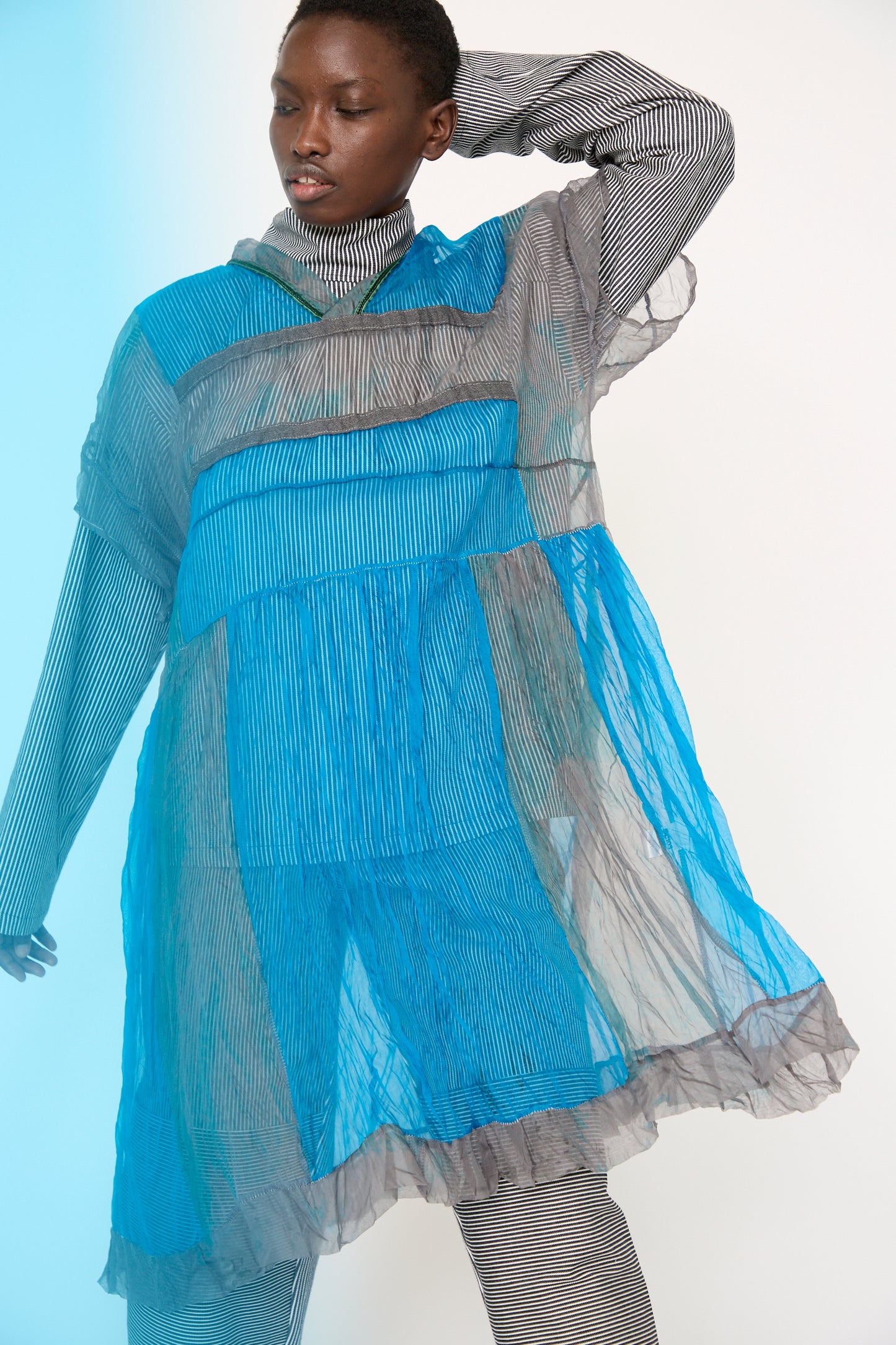 A woman wearing the Silk Organza Glory Dress in Glacial by SC103, poses with one arm behind her head.