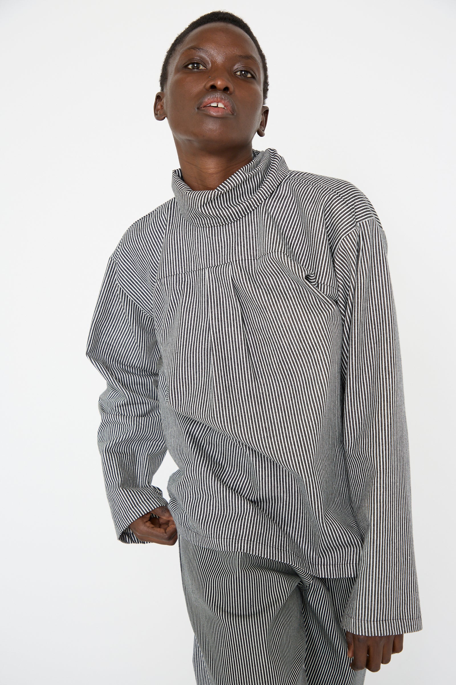 A woman wearing the SC103 Stripe Denim Compass Blouse in Railroad, posing against a plain white background, looking forward.