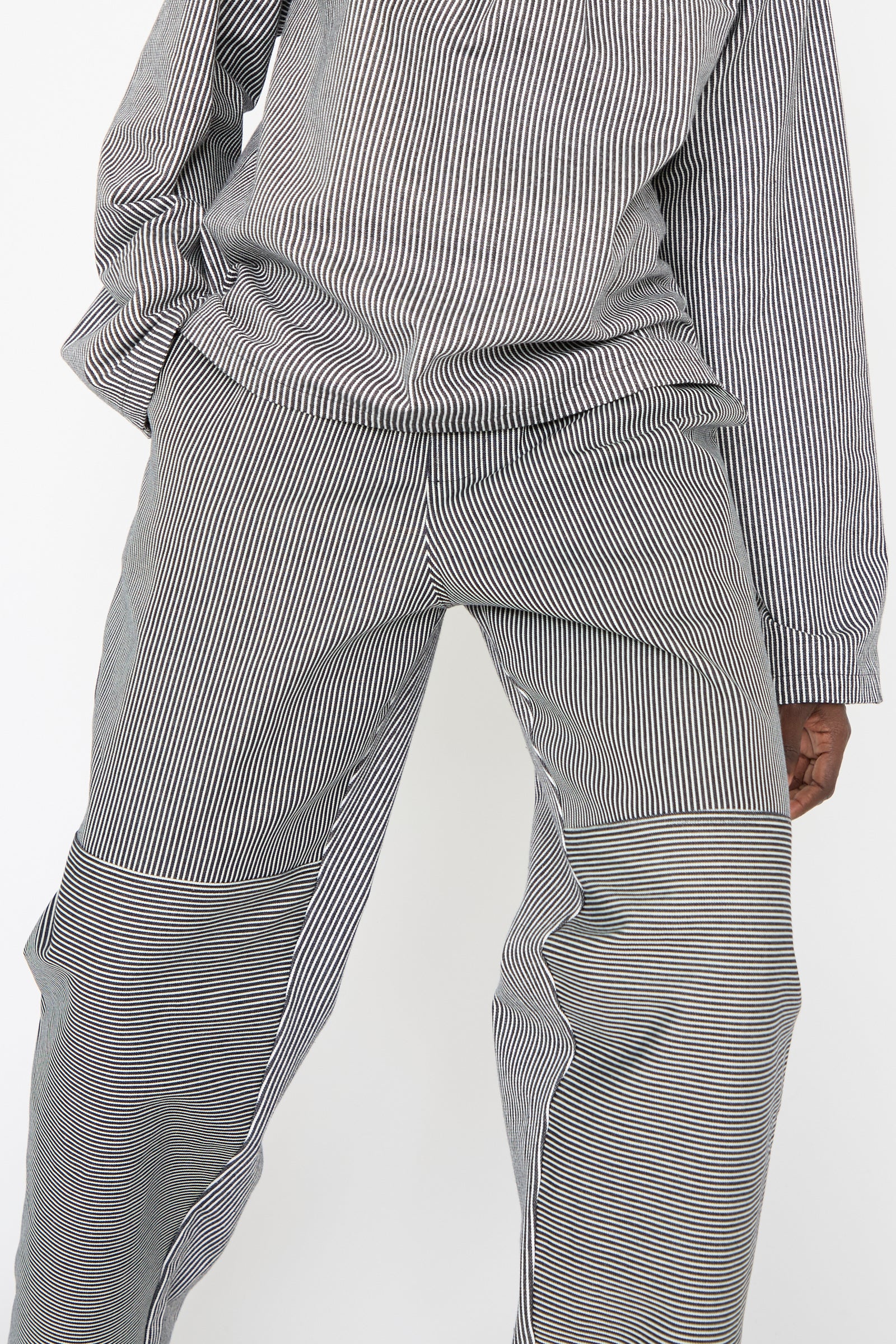 A woman wearing the Stripe Denim Dispatch Pant in Railroad by SC103, showcasing a black and white striped set made from cotton with a relaxed fit, featuring long sleeves and matching pants with an elasticated waist.