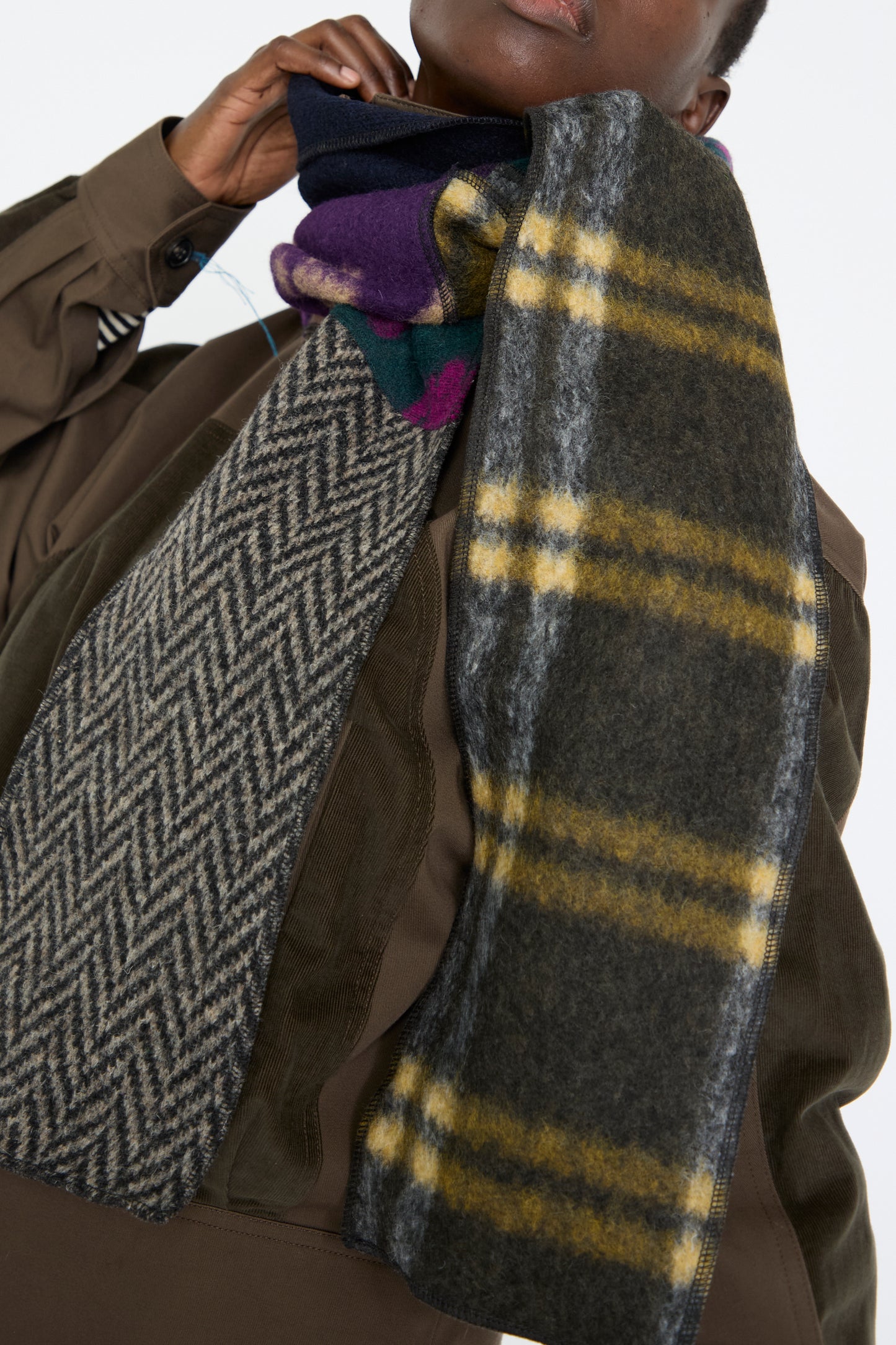 A close up of a woman wearing a brown jacket, overlayed with the Wool Mix Ladder Scarf in Attic from SC103.