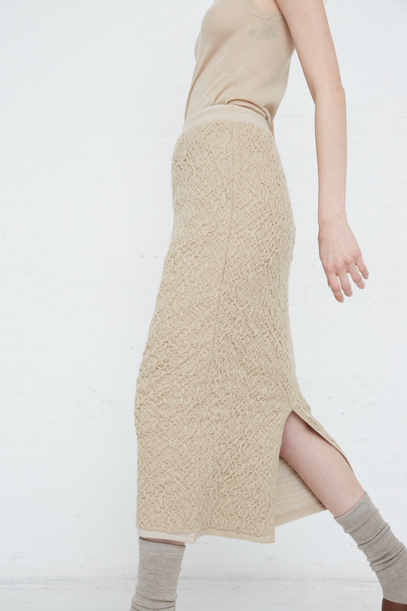 A woman wearing a Baby Alpaca Gauze Skirt in Antique by Lauren Manoogian and knit socks. Side view.