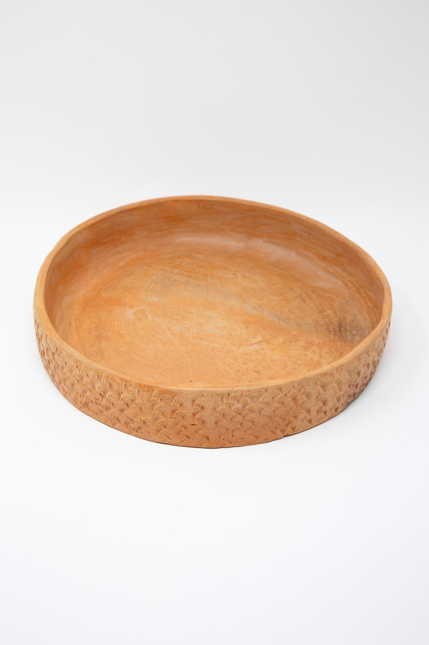 A round wooden bowl on a Julia Frutero Platter in Red Clay by Plaza Bolivar.