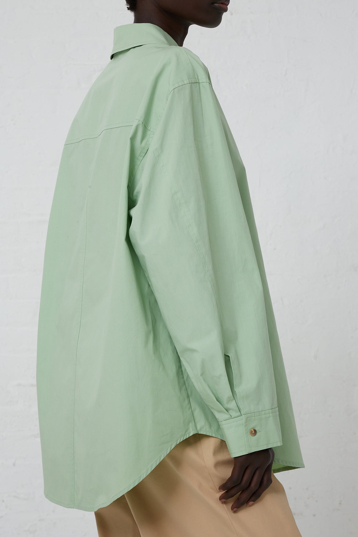 The back of a woman wearing an Organic Cotton Caprice Shirt in Mint by Rejina Pyo with a front button closure.
