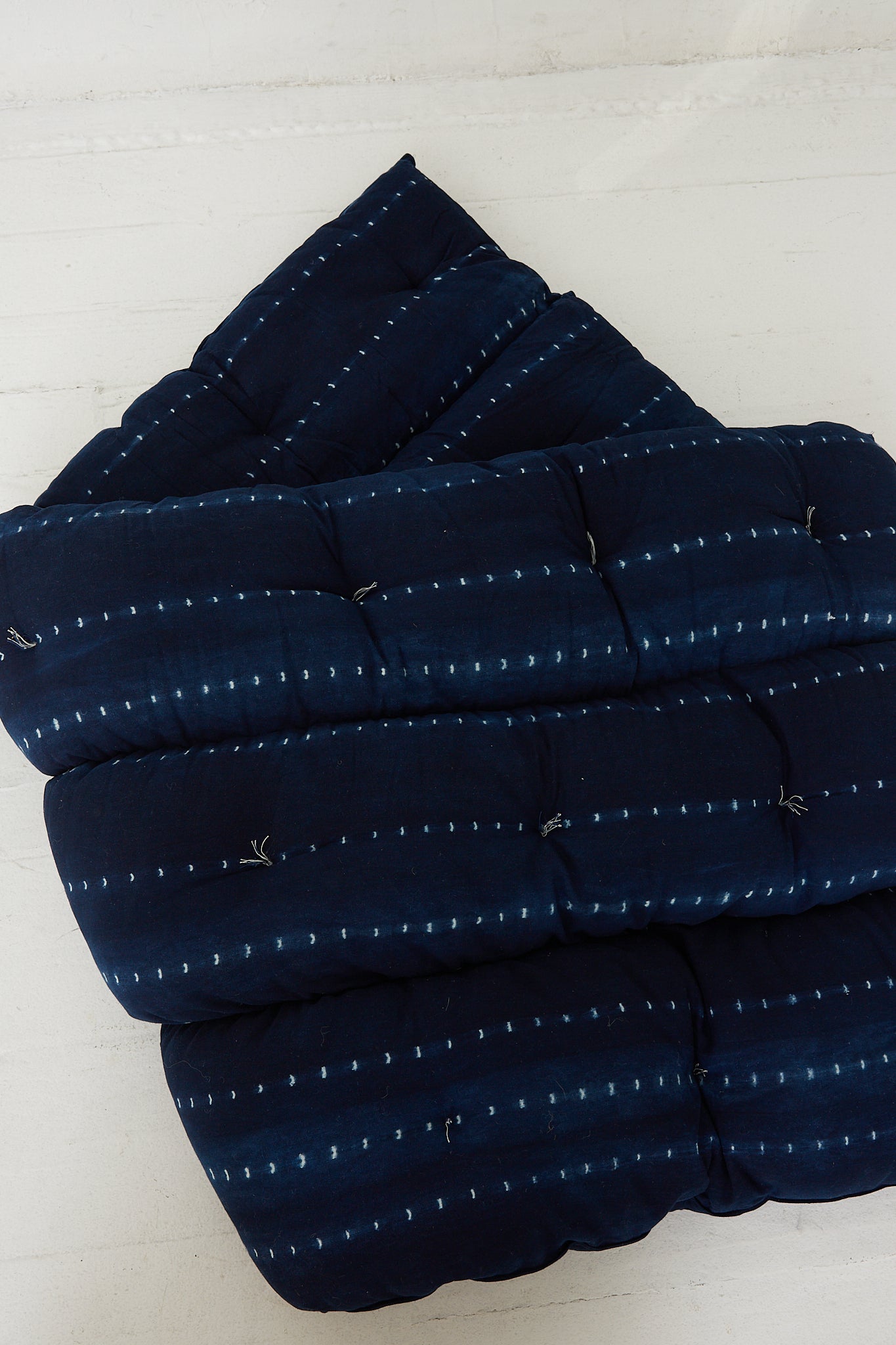 A Tufted Overlay Mattress in Dark Indigo Tie Dye by Tensira folded.