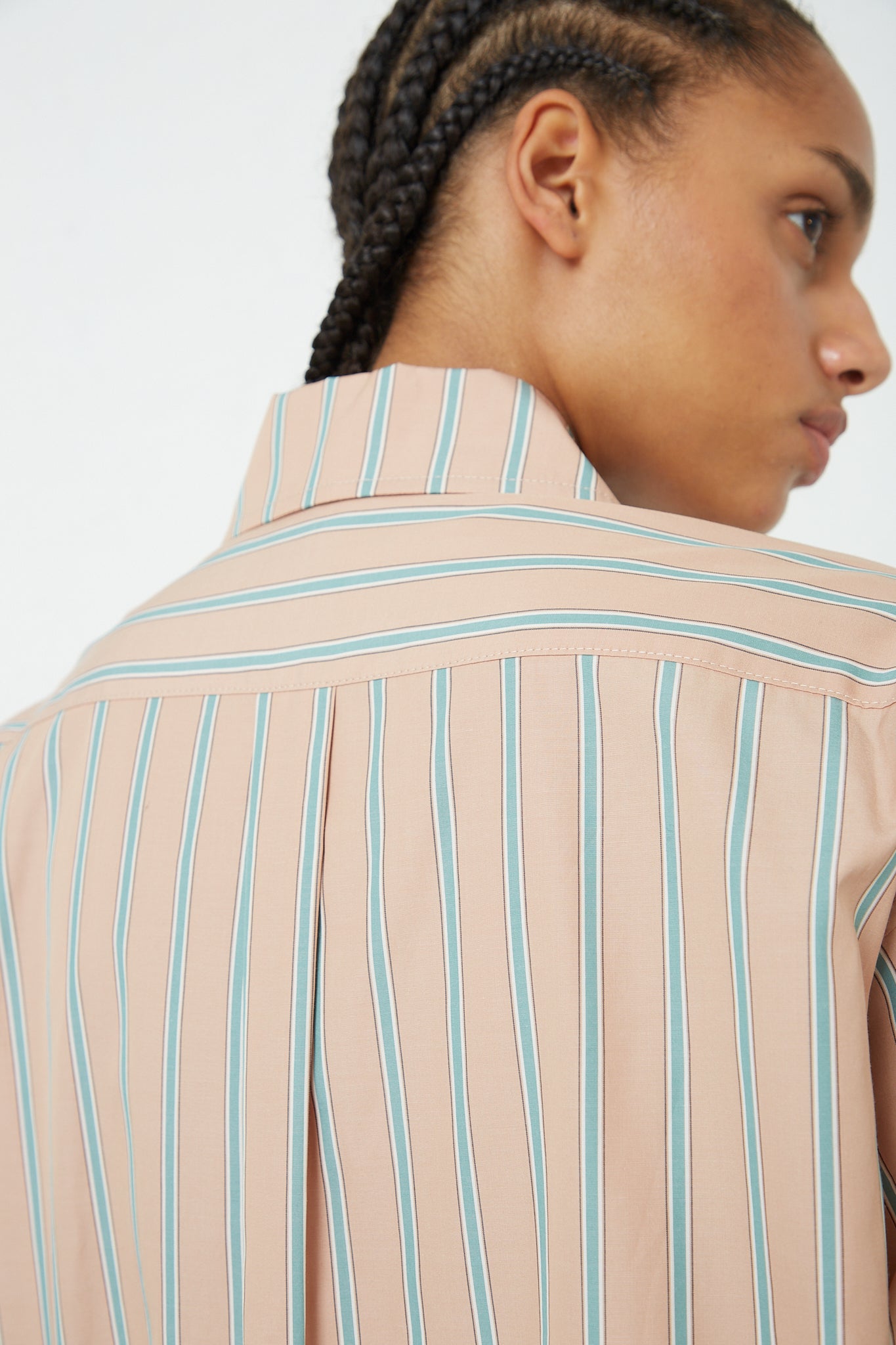 The back of a woman wearing a Rachel Comey Stripe Broadcloth Risa Top in Terracotta, a menswear-inspired shirt in yarn-dyed striped cotton shirting.
