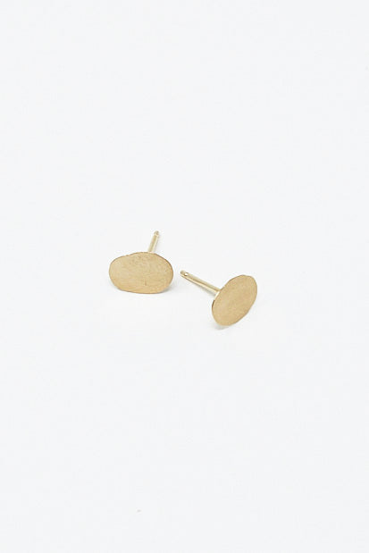A pair of Kathleen Whitaker Foil Stud 7mm Single Earrings in 14K Yellow Gold plated stud earrings on a white surface in Los Angeles.